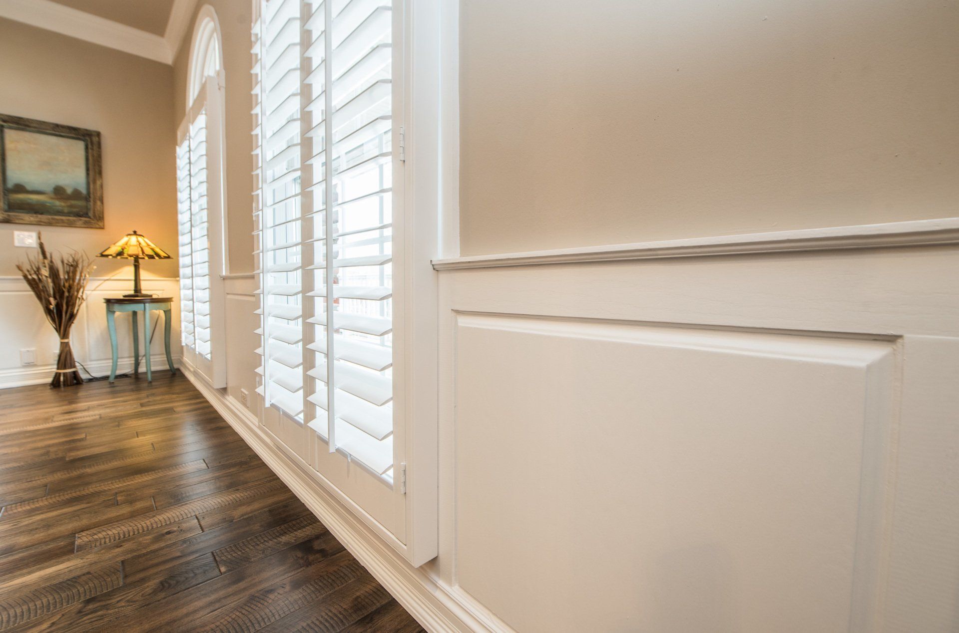 a living room with hardwood floors and white shutters on the windows .