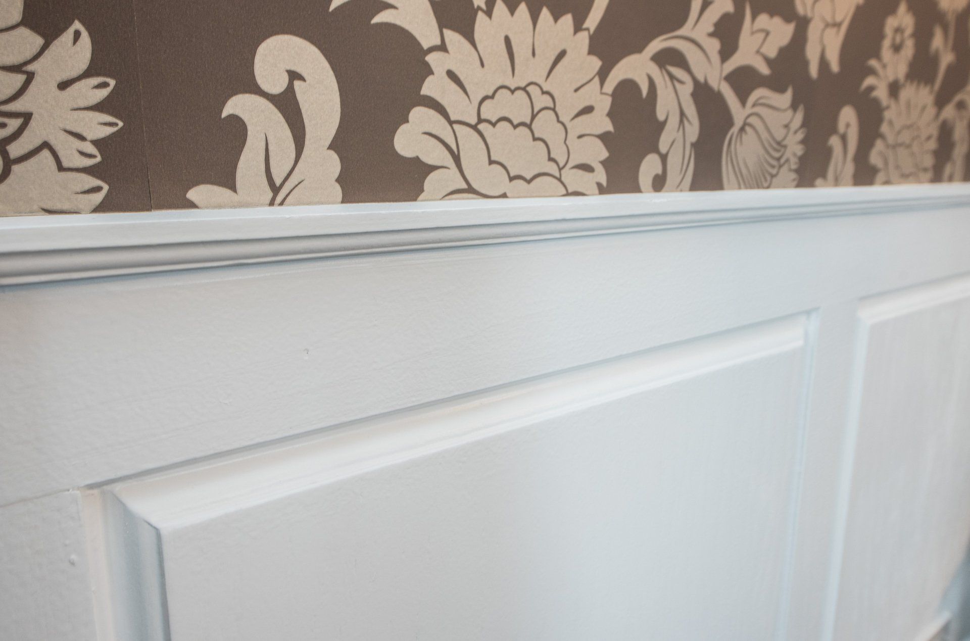 a close up of a white cabinet with a floral wallpaper behind it