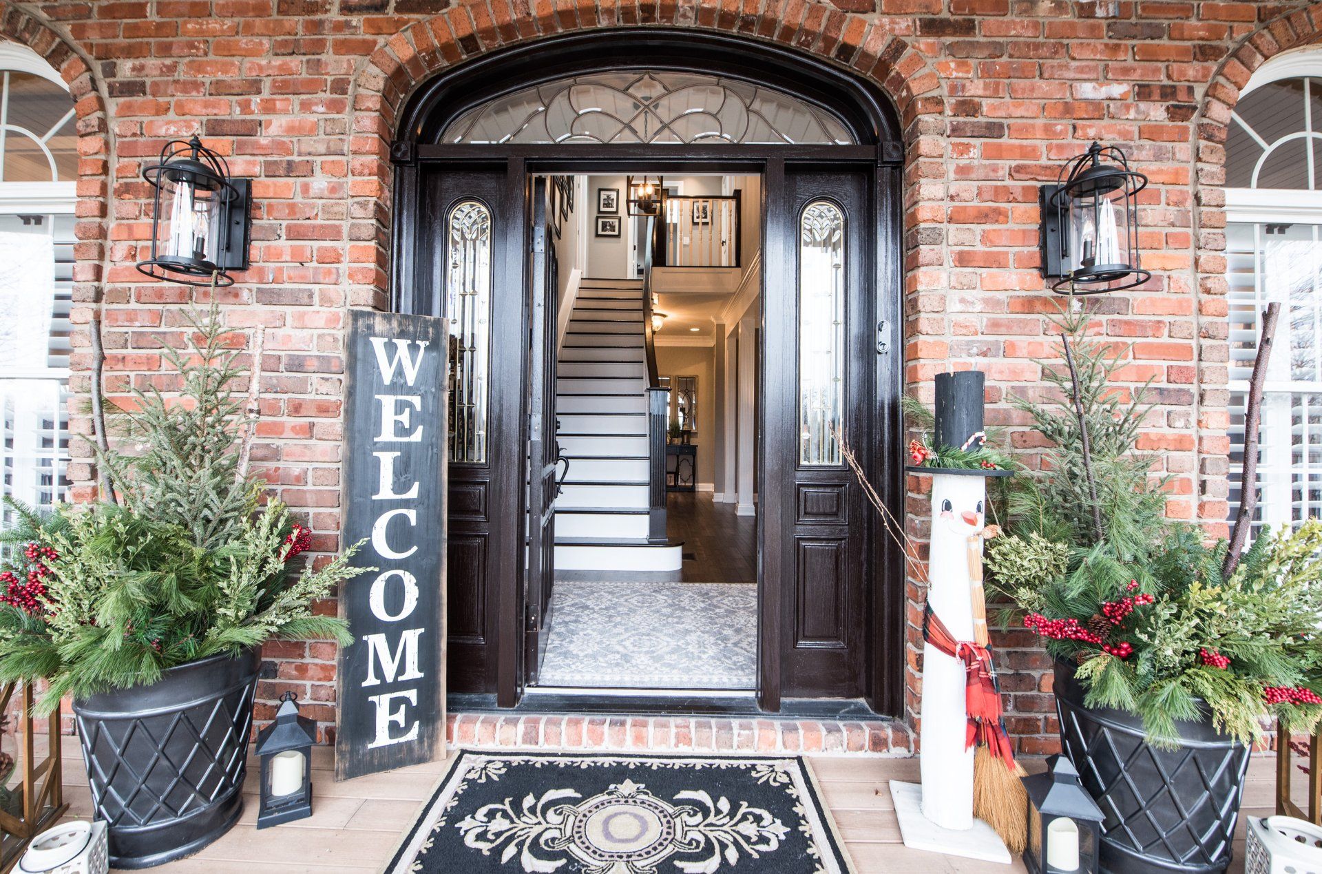 the front door of a brick house decorated for christmas with a welcome sign .