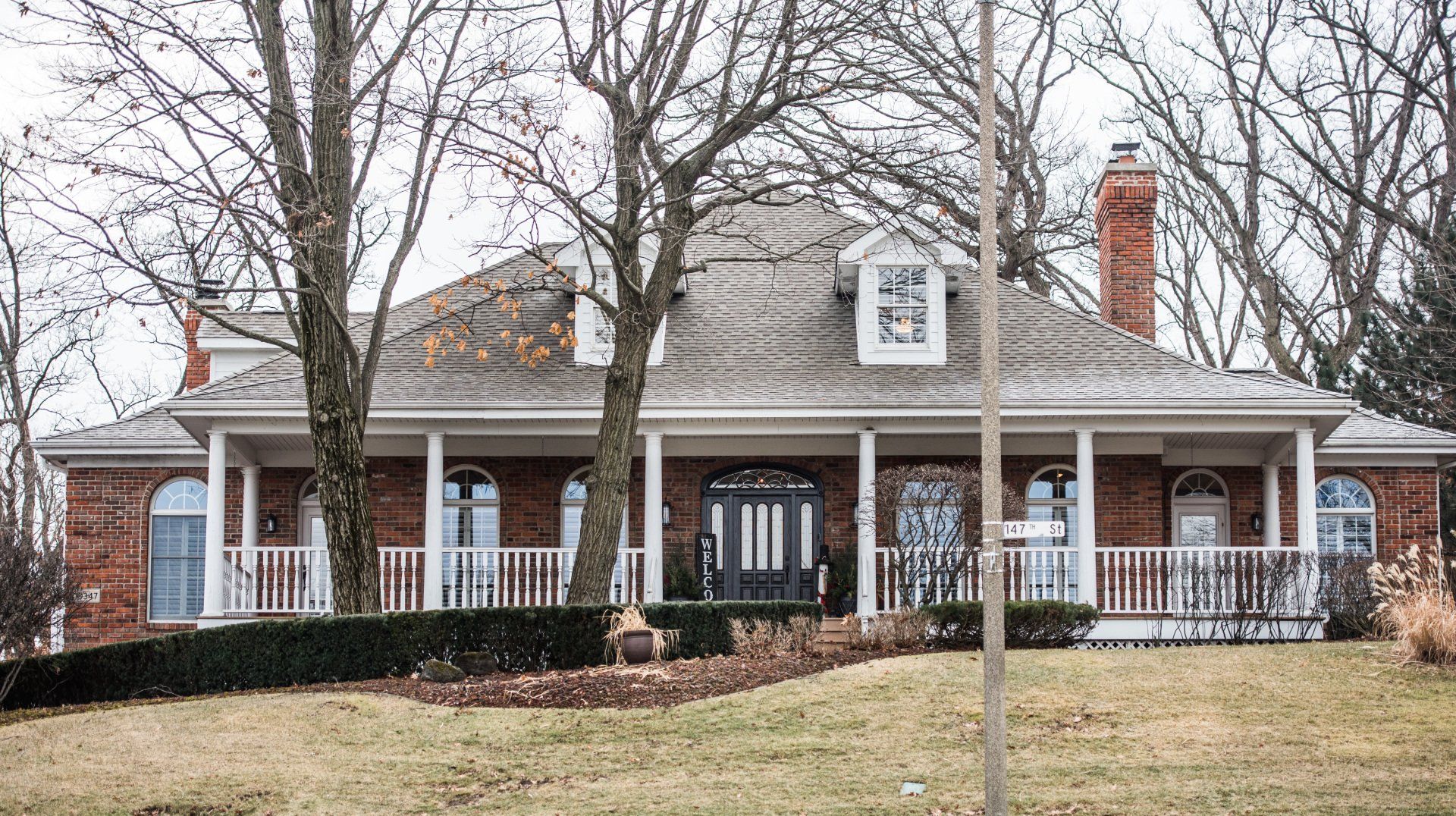 a large brick house with a porch and trees in front of it .