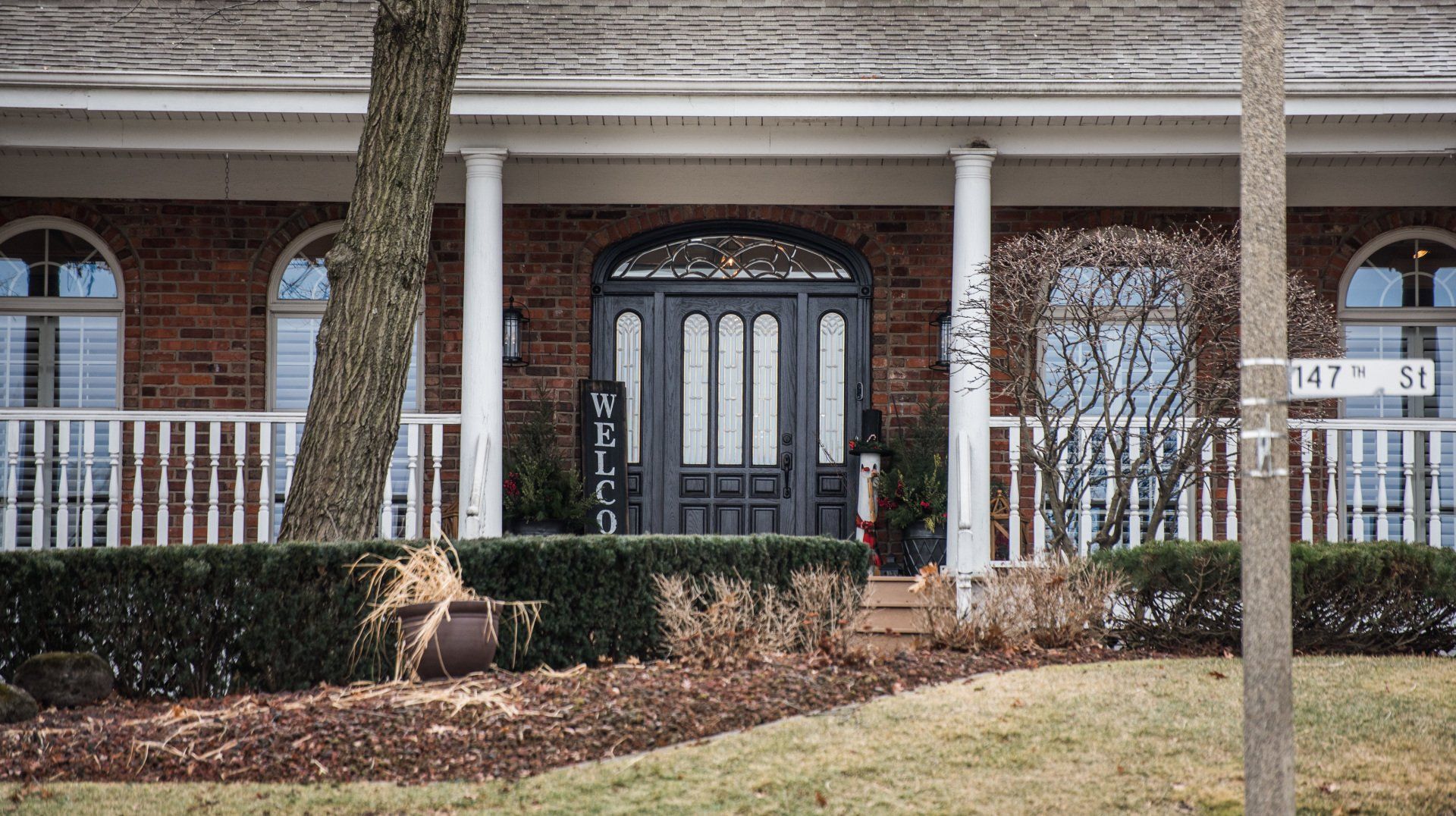 a brick house with a large porch and a black front door .