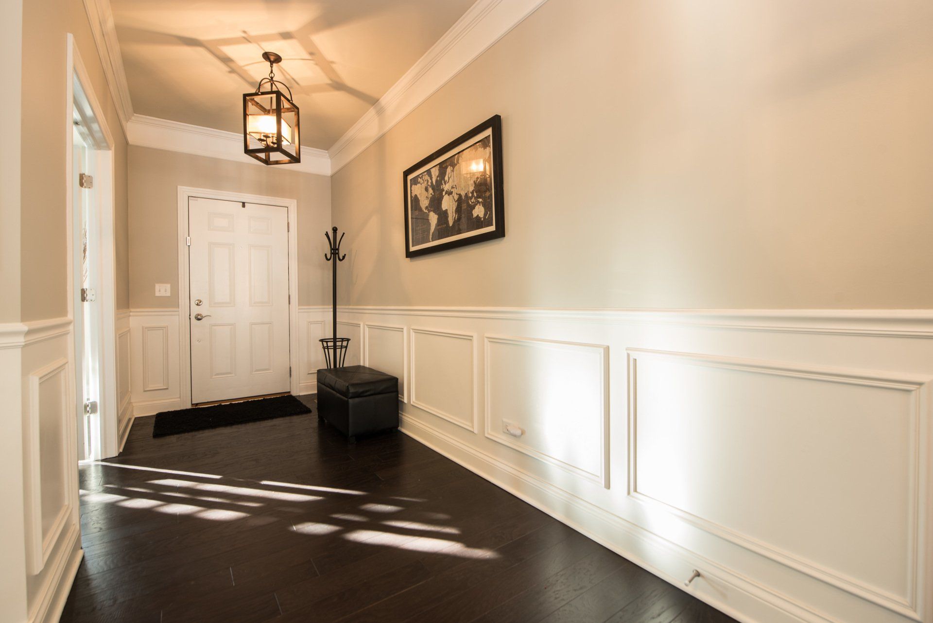 a hallway with a picture on the wall and a lantern hanging from the ceiling .