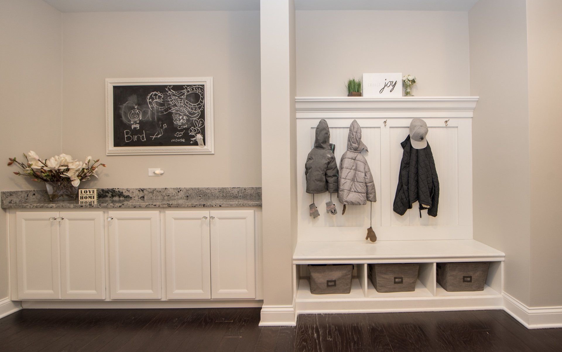 a mud room with a bench and a chalkboard on the wall .