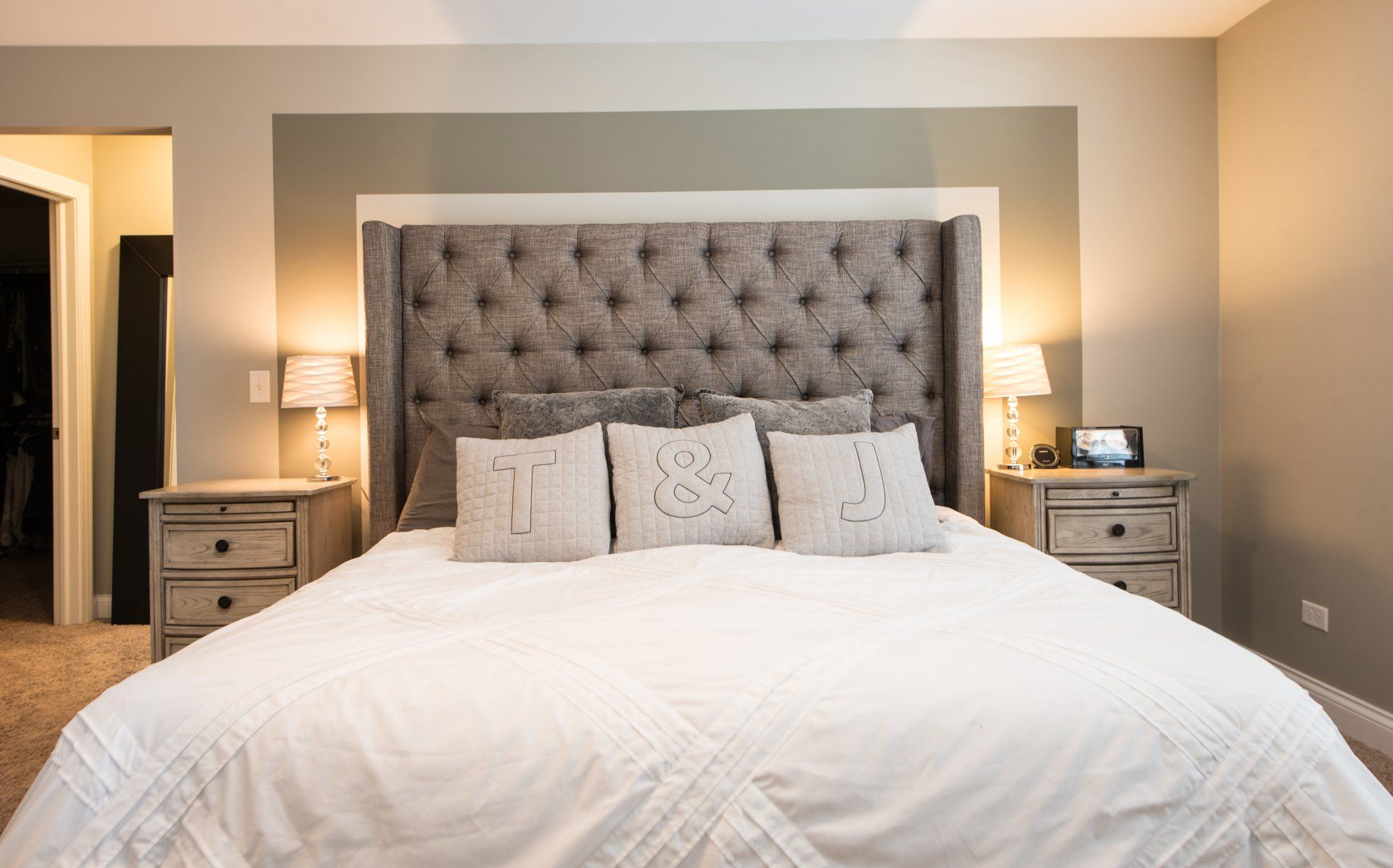a bedroom with a bed , nightstands , lamps and a tufted headboard .