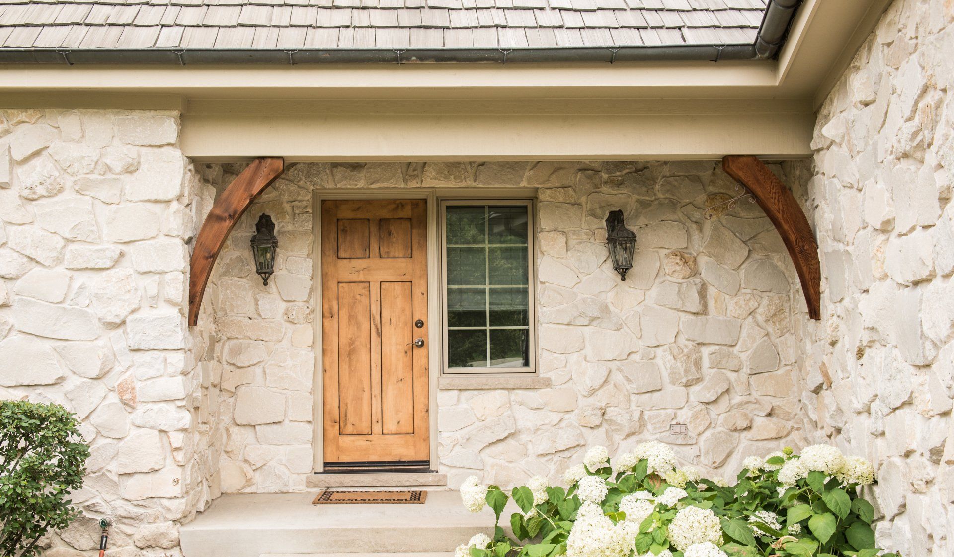 the front door of a stone house with a wooden door and a window .