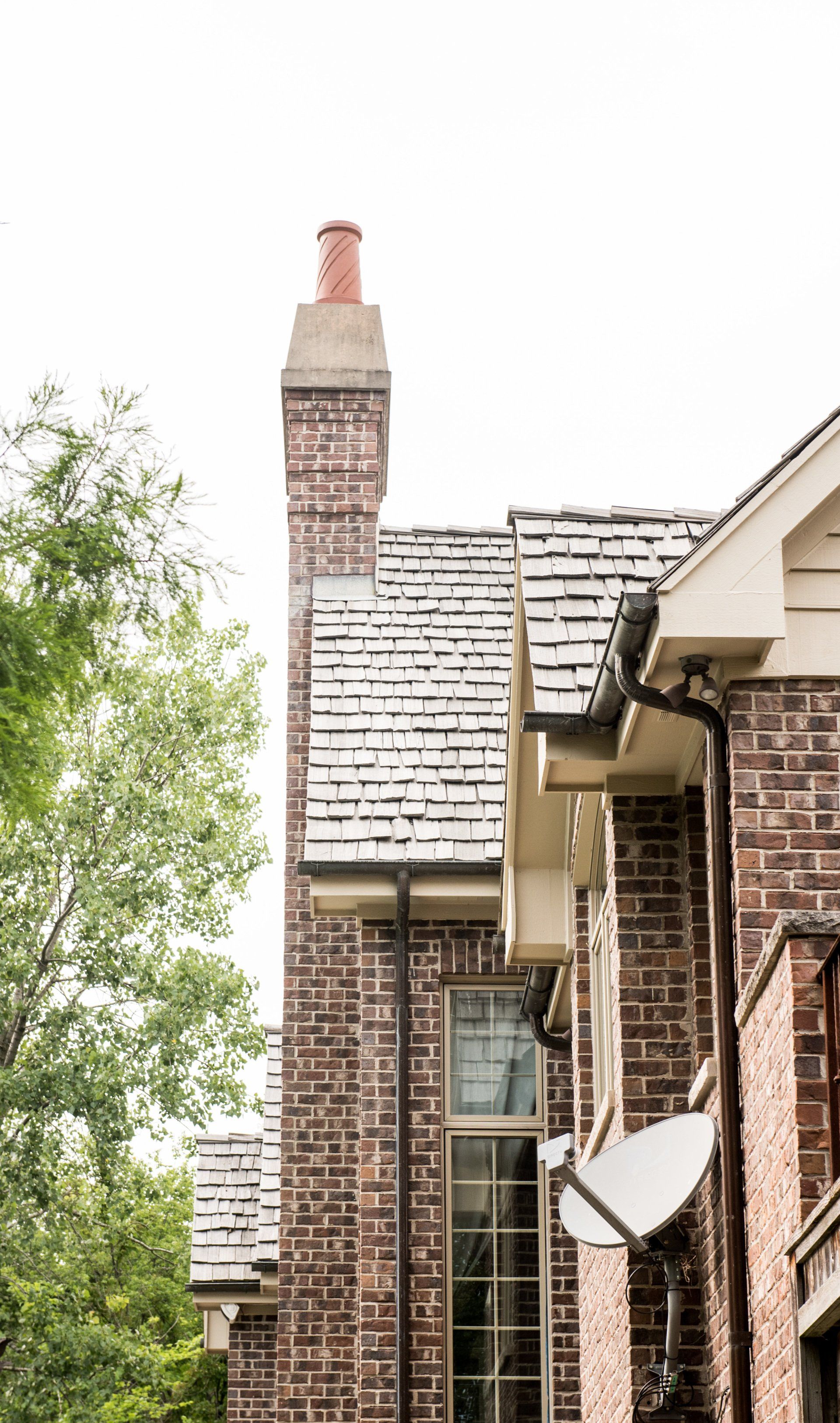 a brick house with a chimney and a satellite dish on the side .