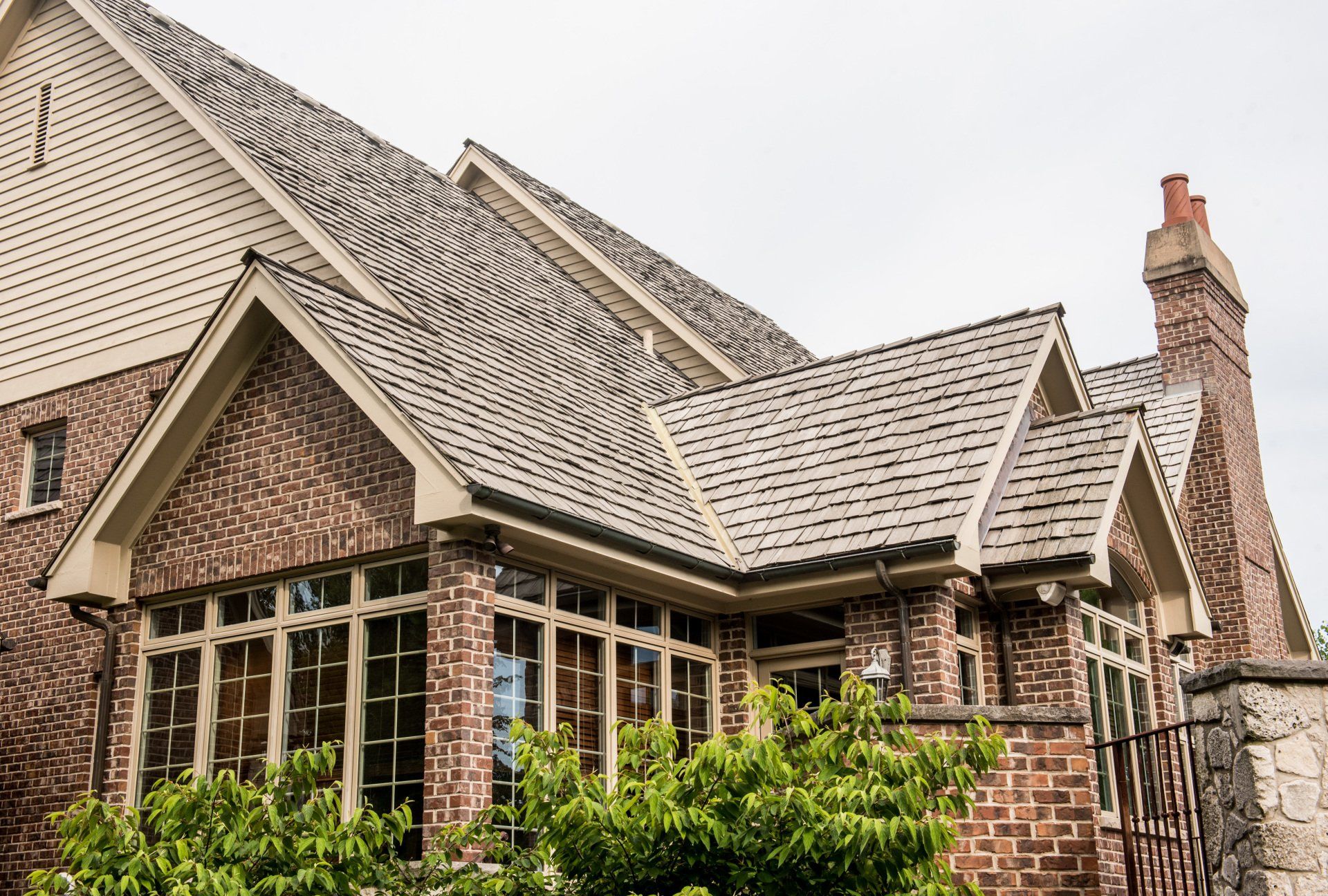 a large brick house with a gray roof and a chimney .