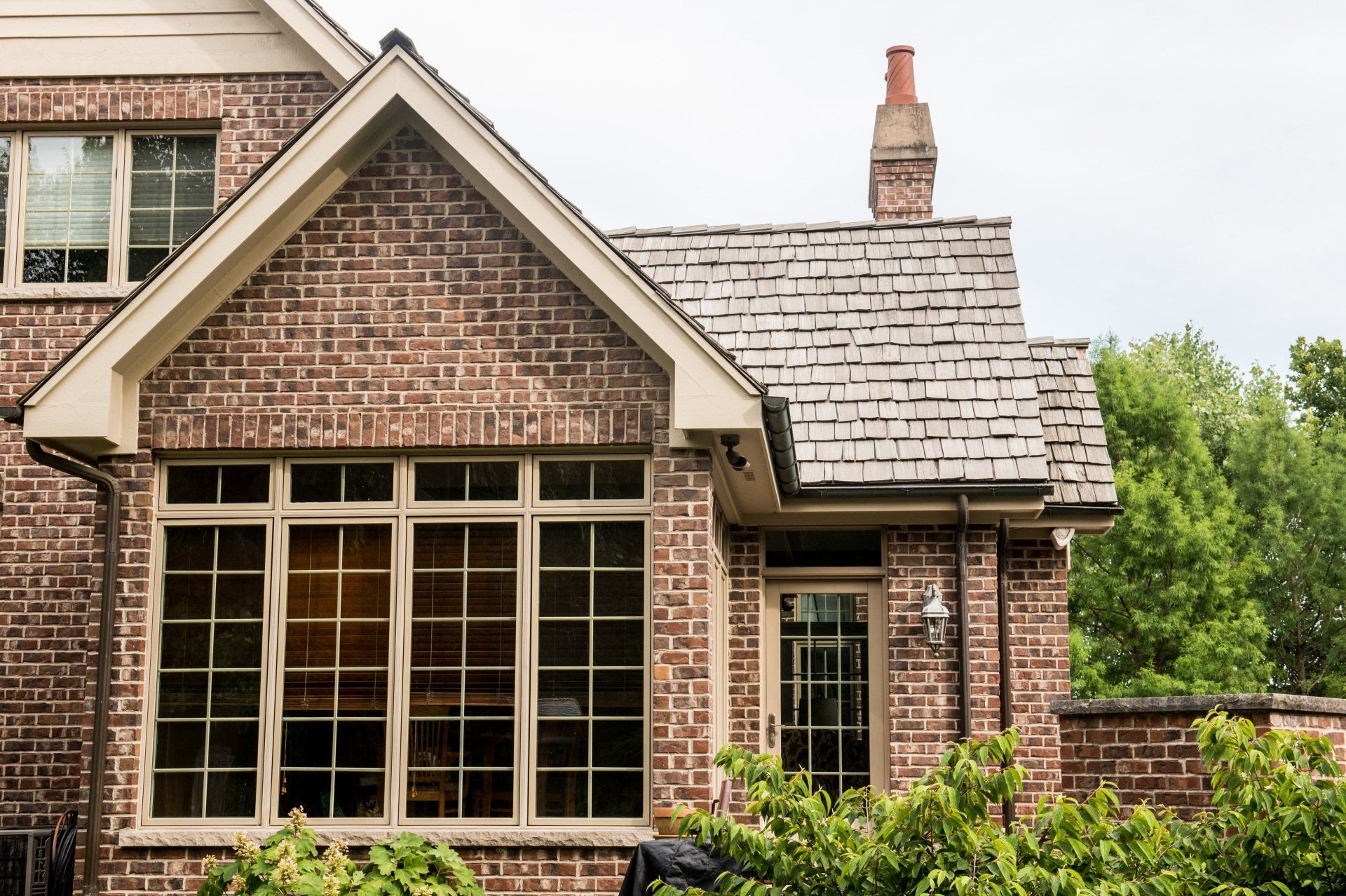 a large brick house with a slate roof and lots of windows .