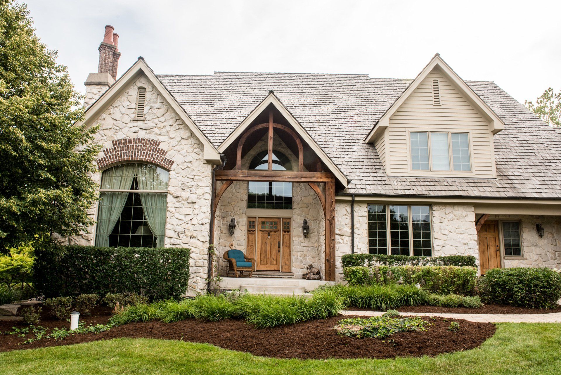 a large brick house with a wooden porch and a large lawn in front of it .