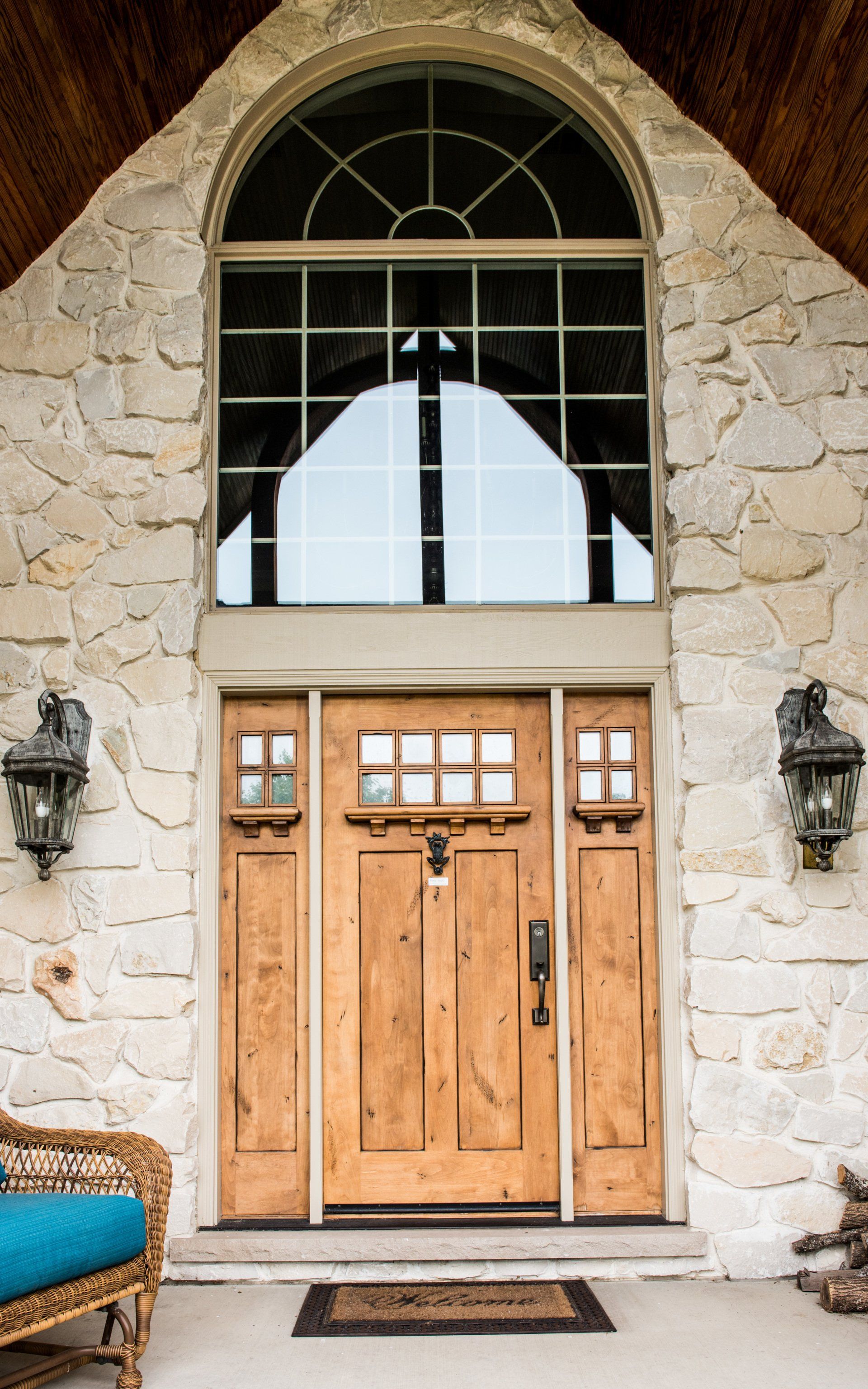 the front door of a stone house with a wooden door and a large window