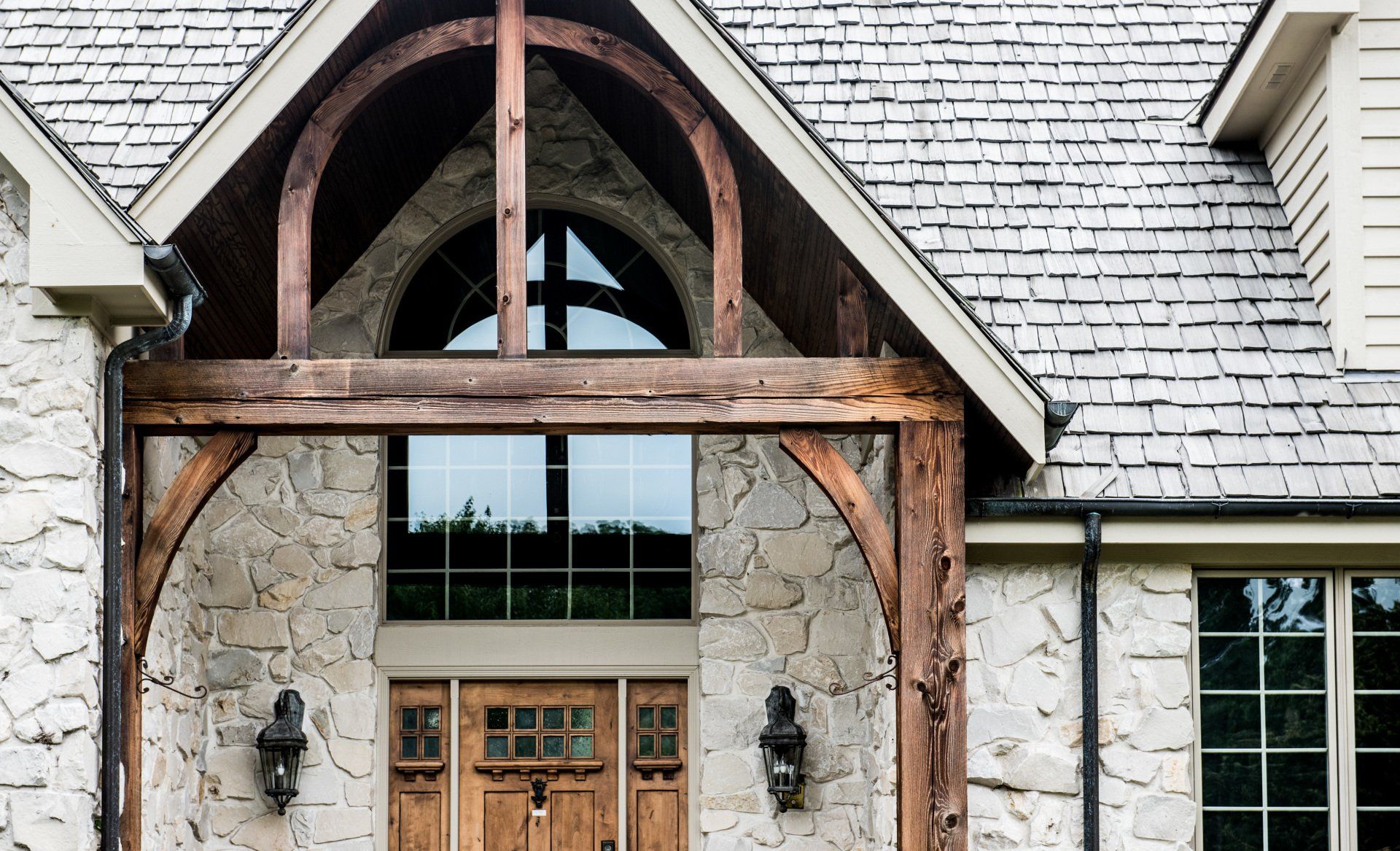 a large stone house with a wooden porch and a slate roof .