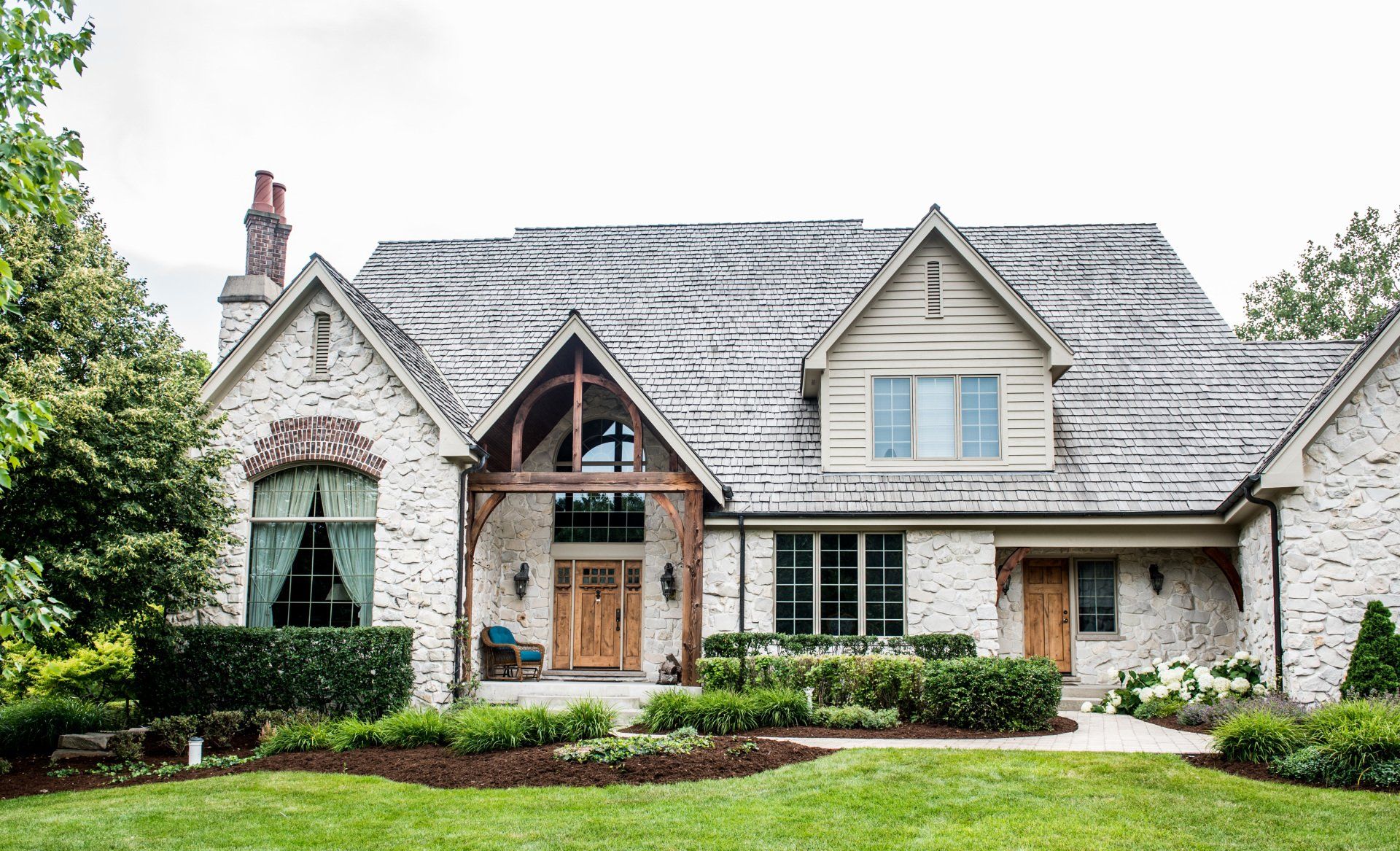 a large white brick house with a slate roof and a large lawn in front of it .