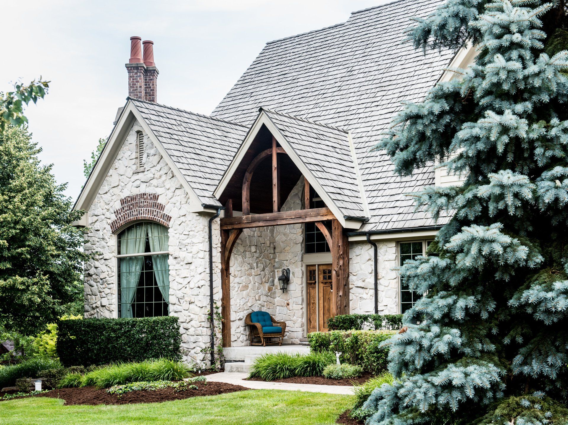 a large white brick house with a gray roof is surrounded by trees .