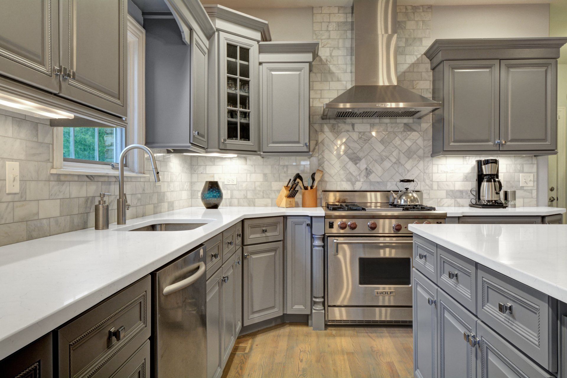 a kitchen with gray cabinets , stainless steel appliances , and white counter tops .