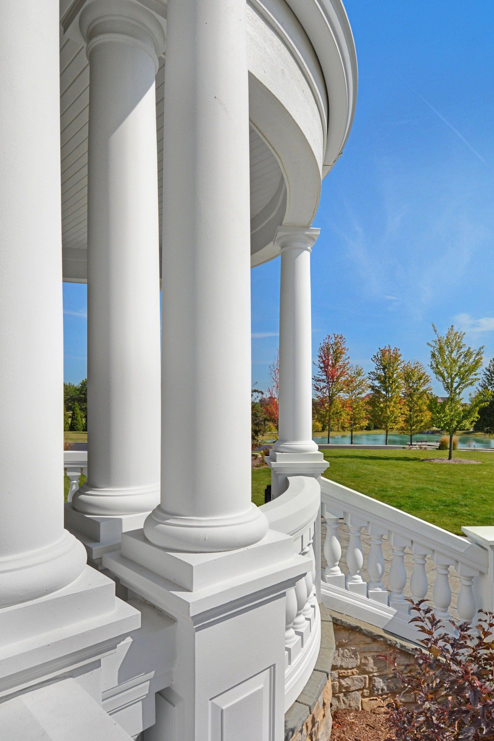a white gazebo with columns and a railing on a sunny day .
