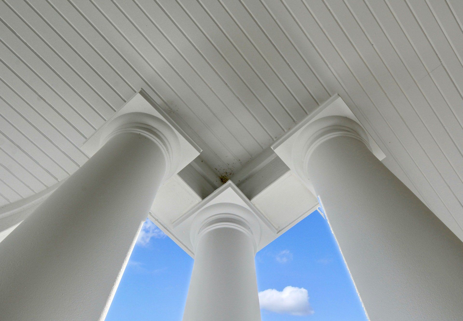 looking up at the columns of a building with a blue sky in the background .