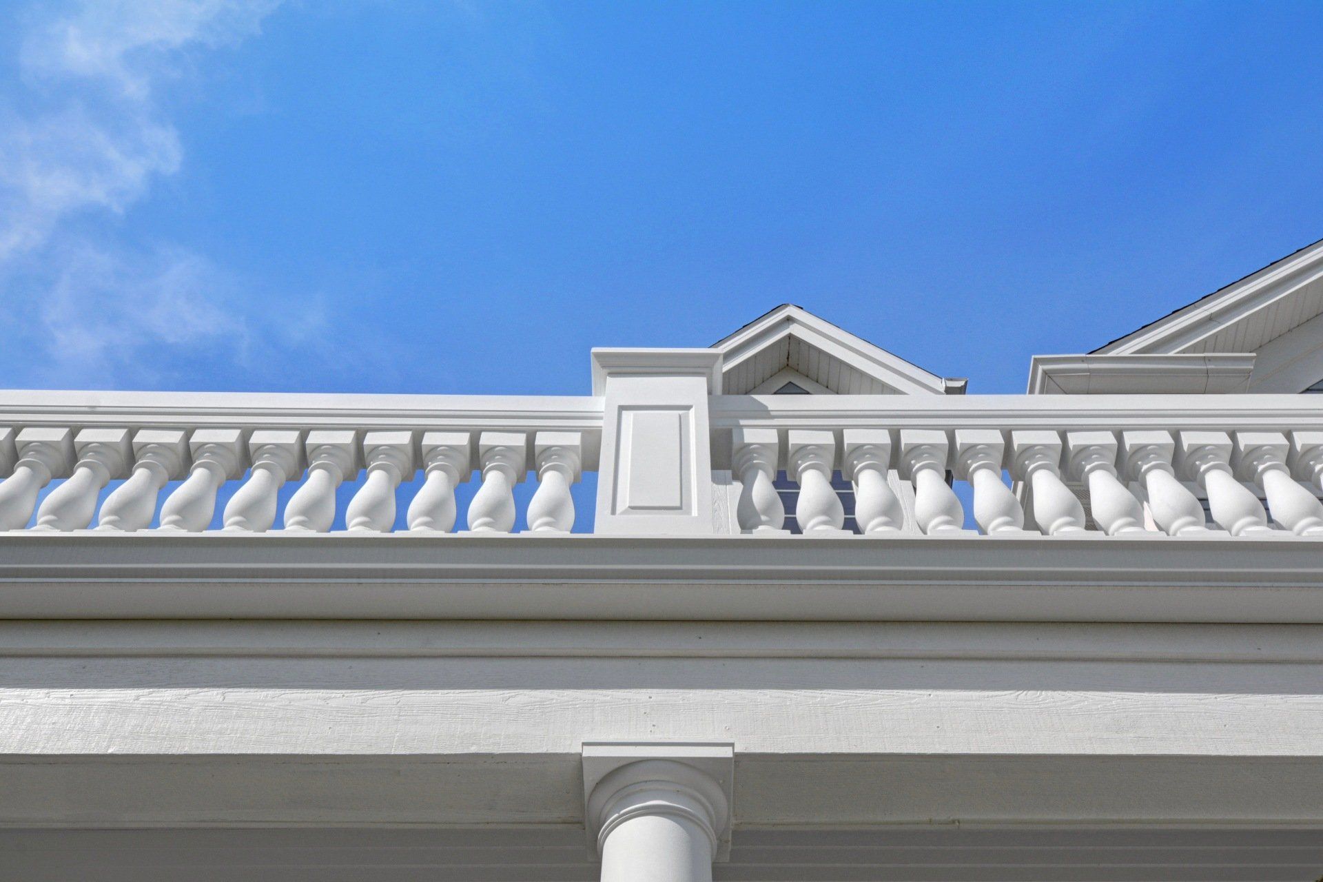 a white building with a balcony and a blue sky in the background .
