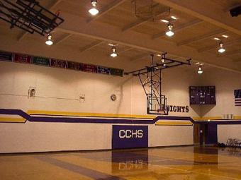 an empty gym with a basketball hoop and a sign that says cchs
