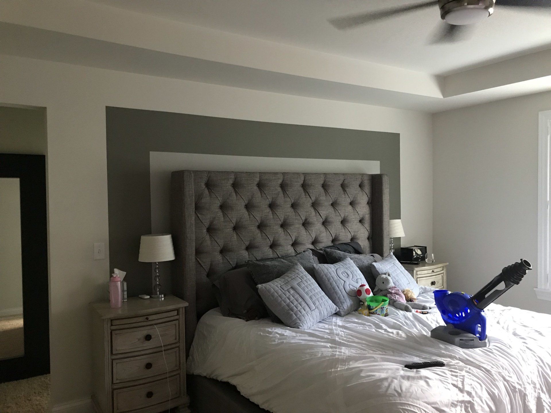 a bedroom with a bed , nightstand , mirror and ceiling fan .