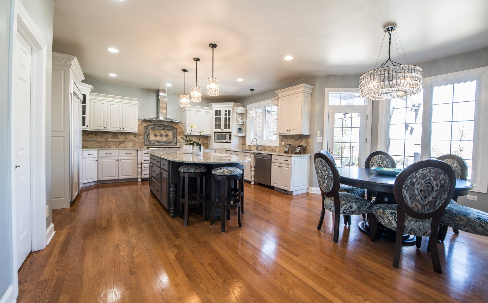 a kitchen and dining room in a house with hardwood floors and white cabinets .