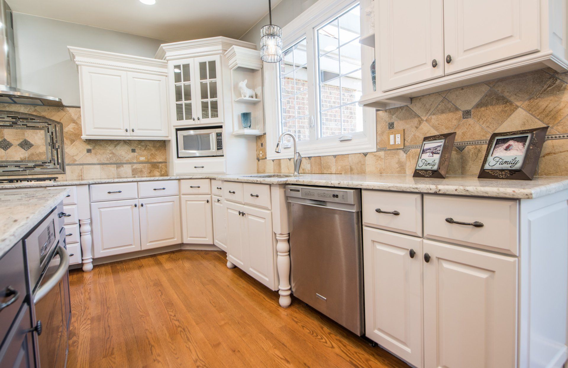 a kitchen with white cabinets , stainless steel appliances , and hardwood floors .