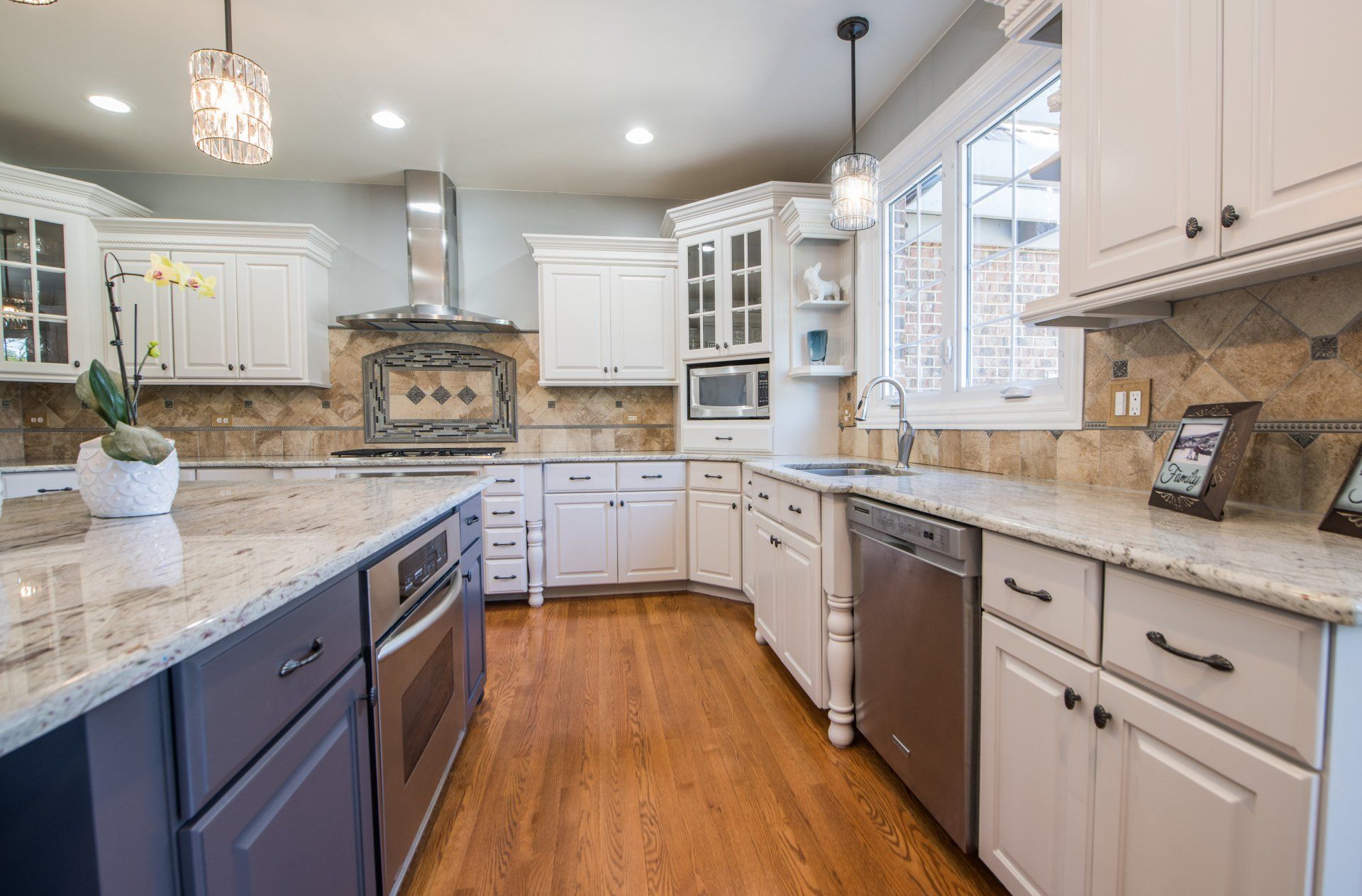 a kitchen with white cabinets , granite counter tops , stainless steel appliances and hardwood floors .