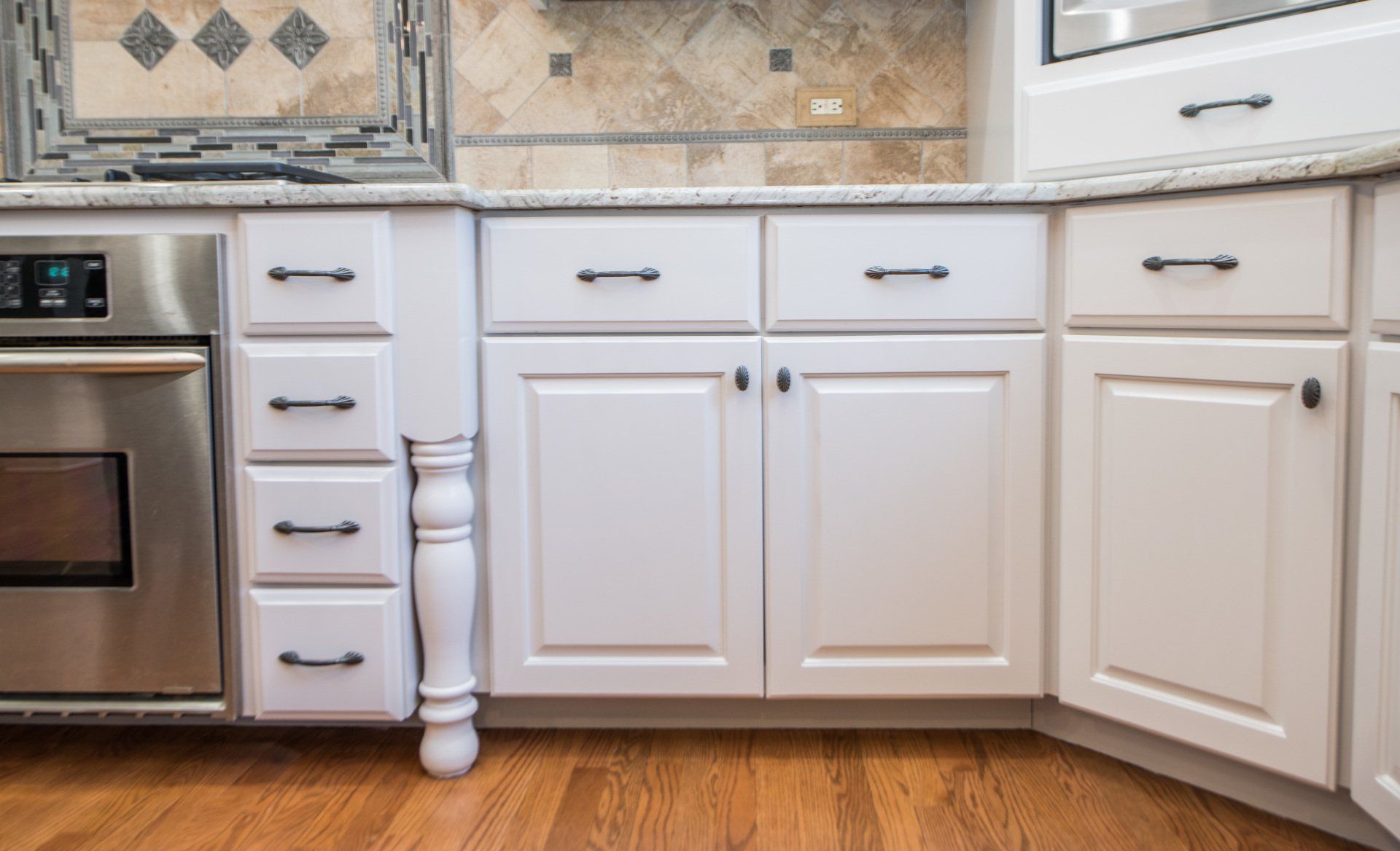 a kitchen with white cabinets , stainless steel appliances , and hardwood floors .