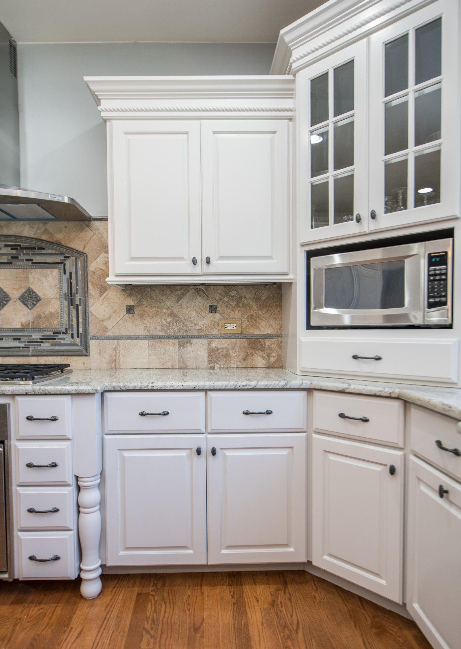 a kitchen with white cabinets , granite counter tops , and stainless steel appliances .