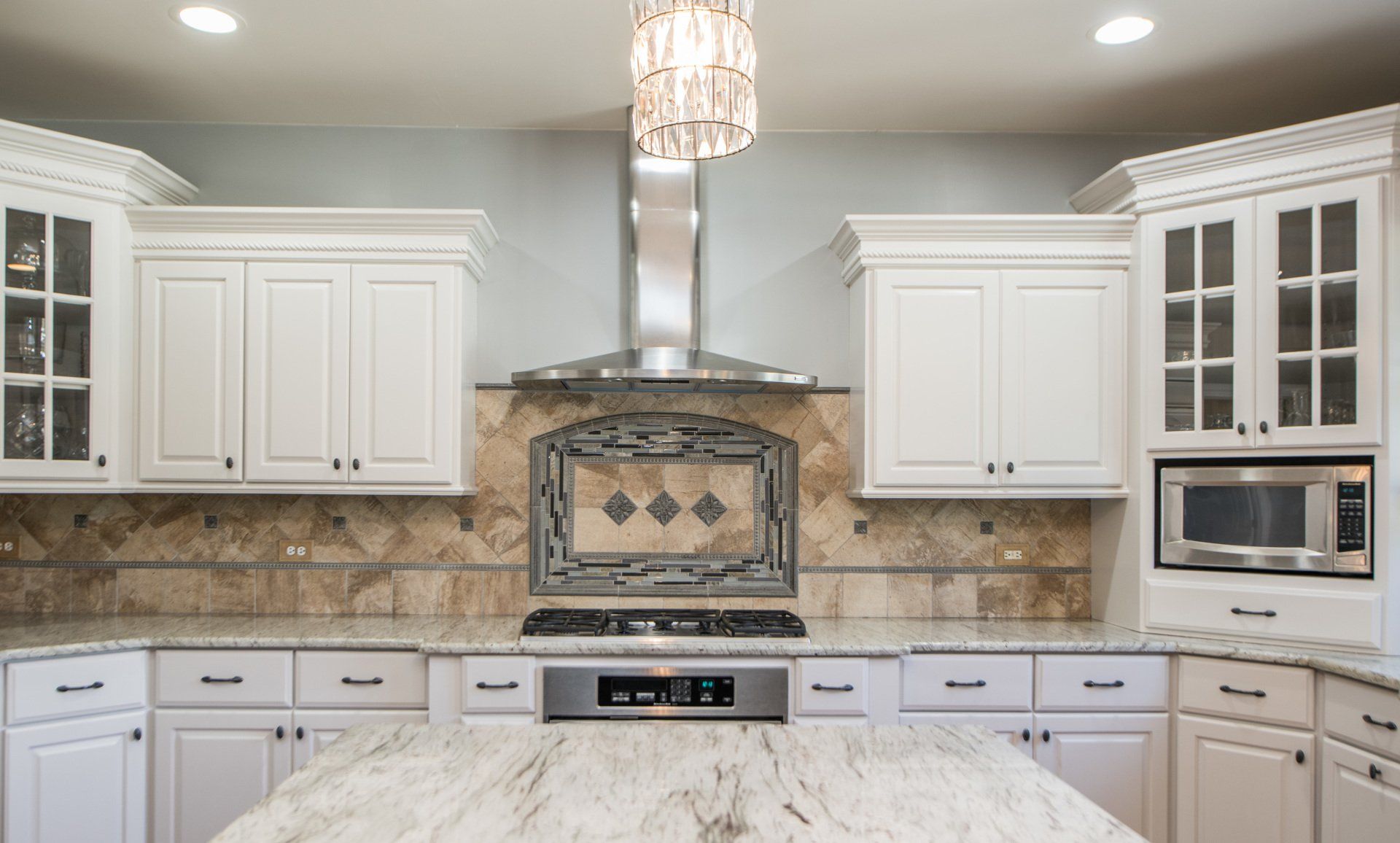 a kitchen with white cabinets , granite counter tops , stainless steel appliances and a large island .