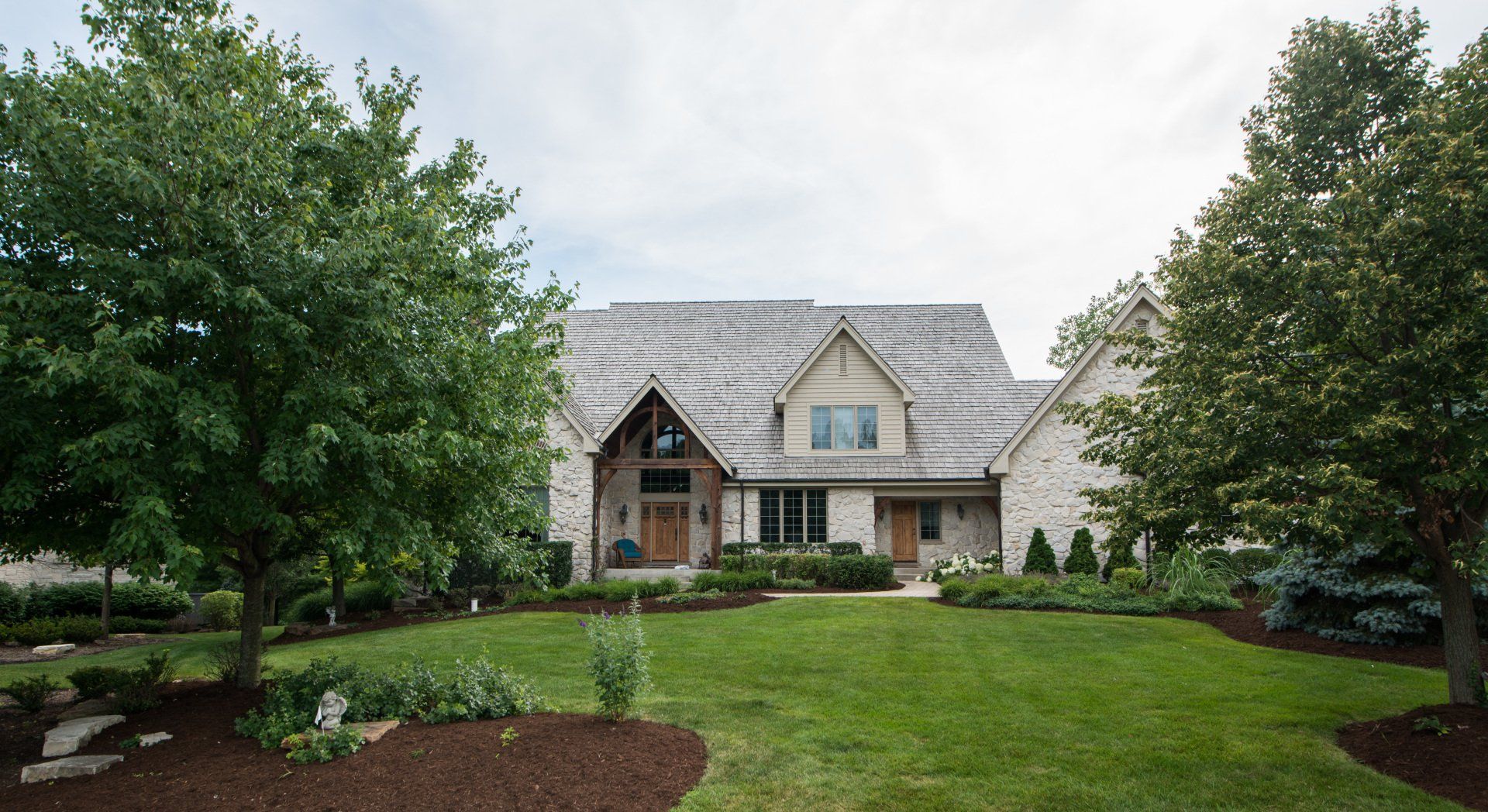 a large house with a lush green lawn and trees in front of it