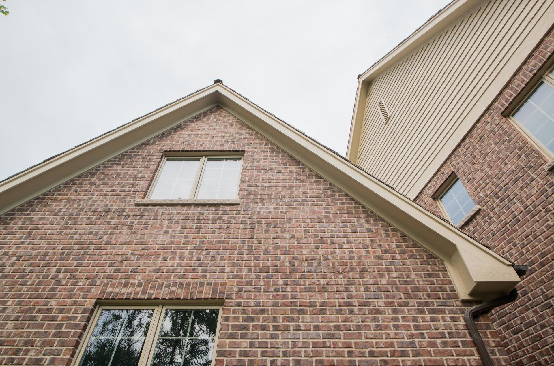 looking up at the roof of a brick house with two windows .