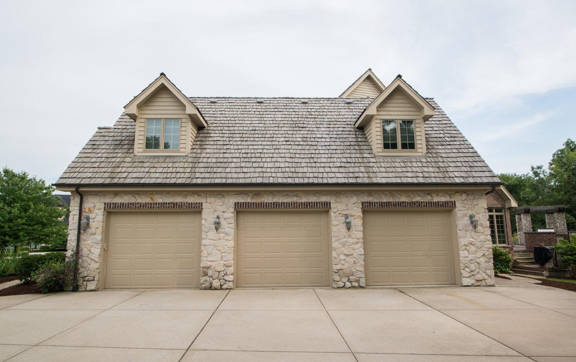 a large house with three garage doors and a wooden roof .