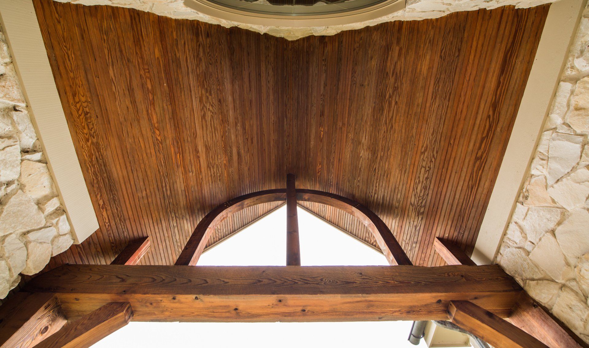 looking up at the ceiling of a building with wooden beams and a window .