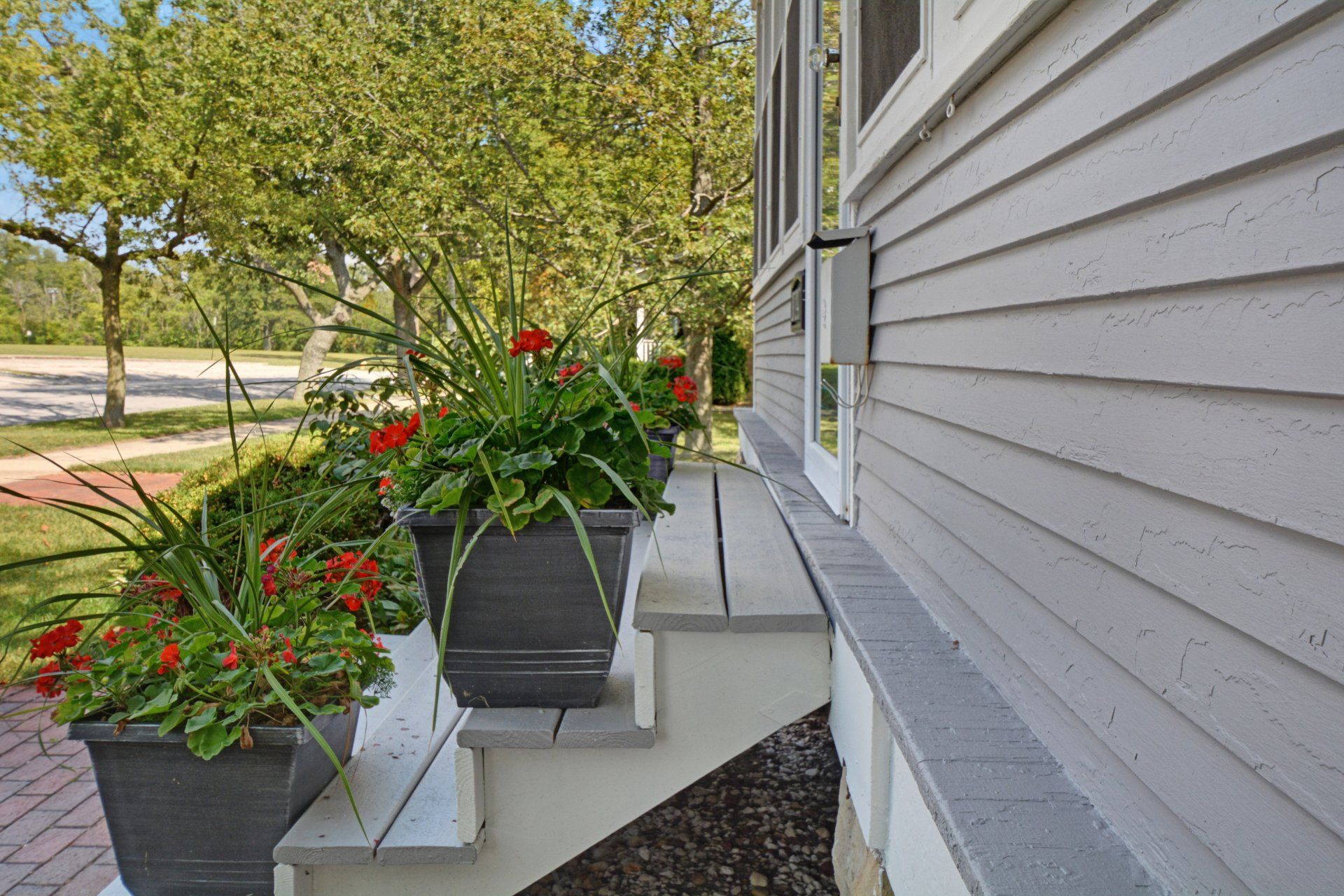 a porch with flowers in pots on the steps of a house .