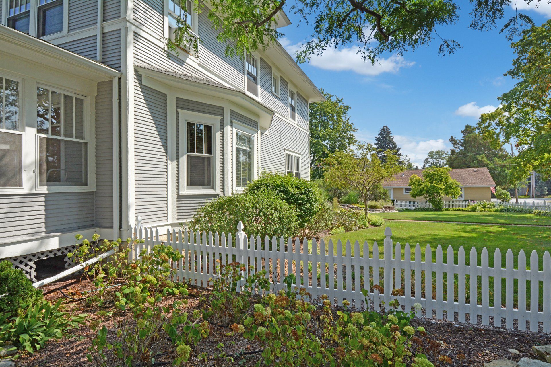 a white picket fence surrounds a large house
