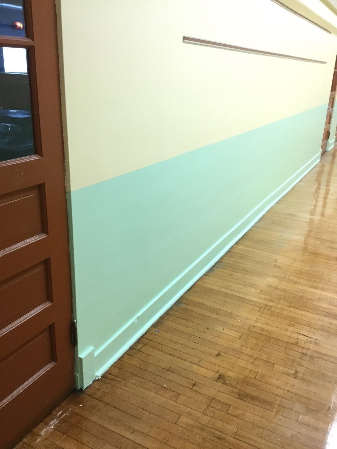 a hallway with a wooden floor and two walls painted different colors