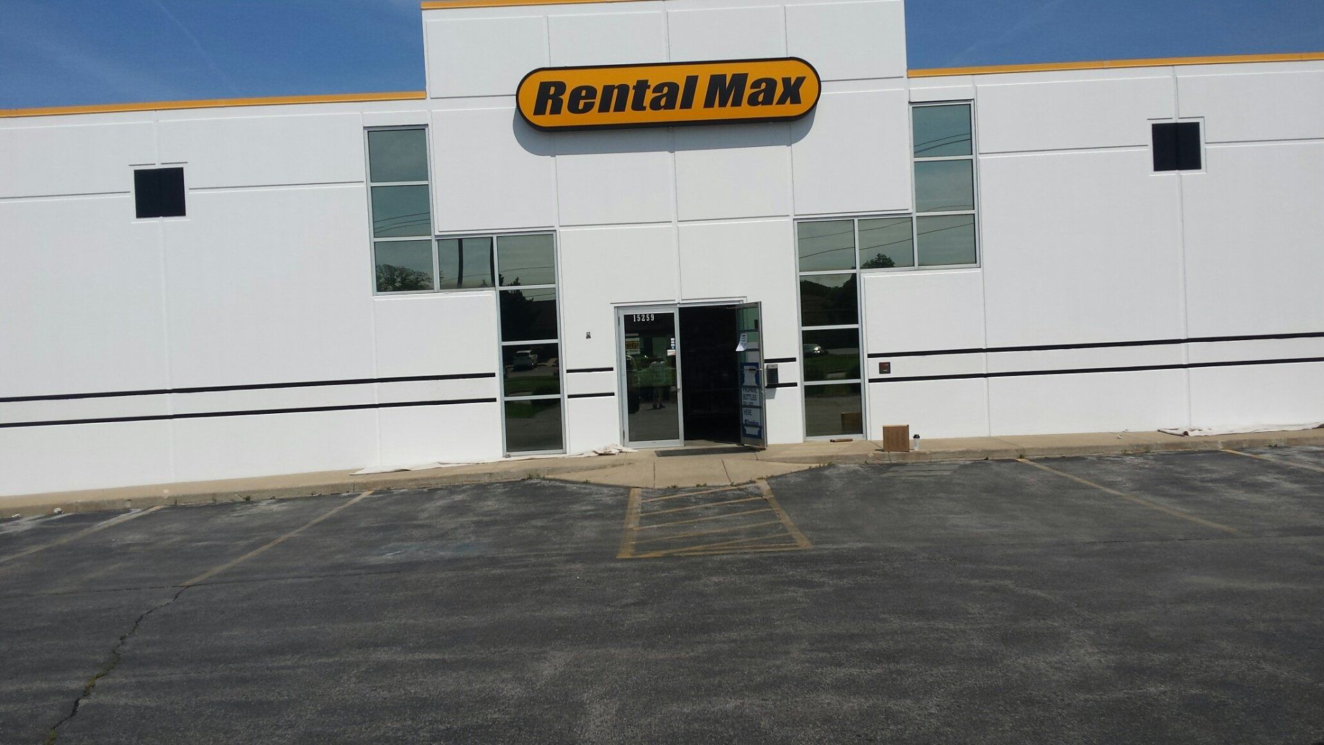 a white building with a yellow sign that says rental max