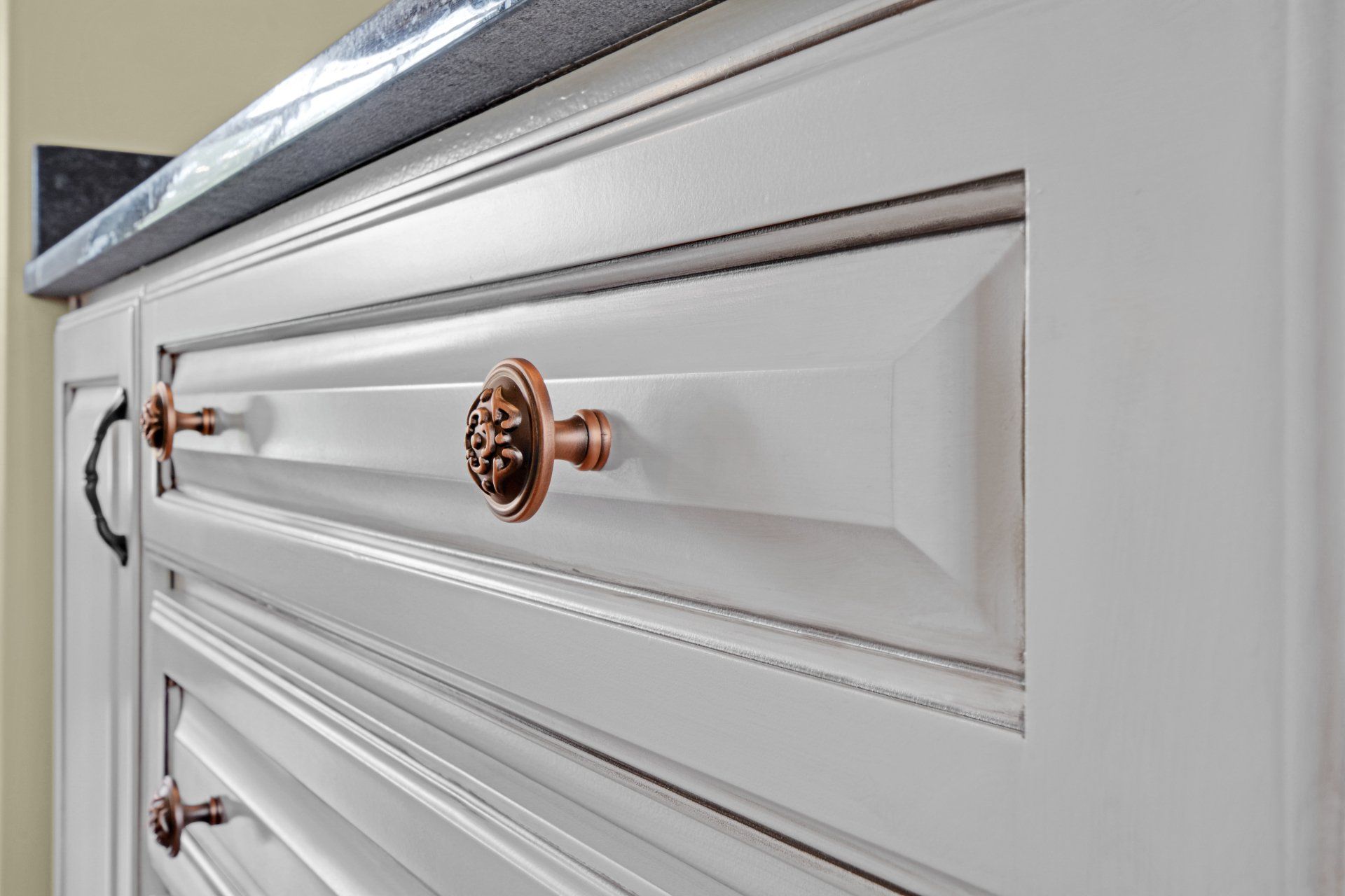 a close up of a white cabinet with copper handles .