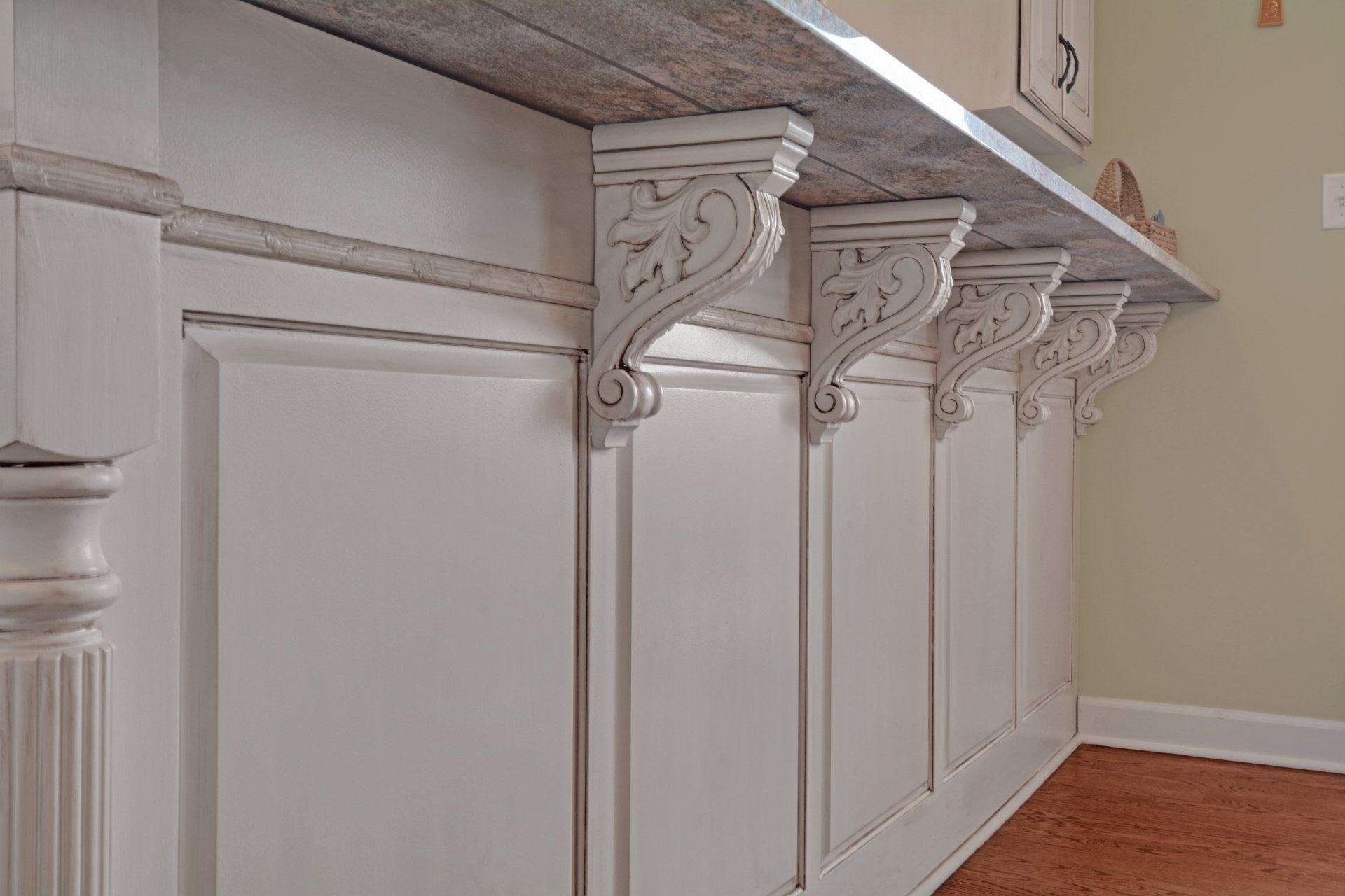 a row of white cabinets with corbels on them in a kitchen .