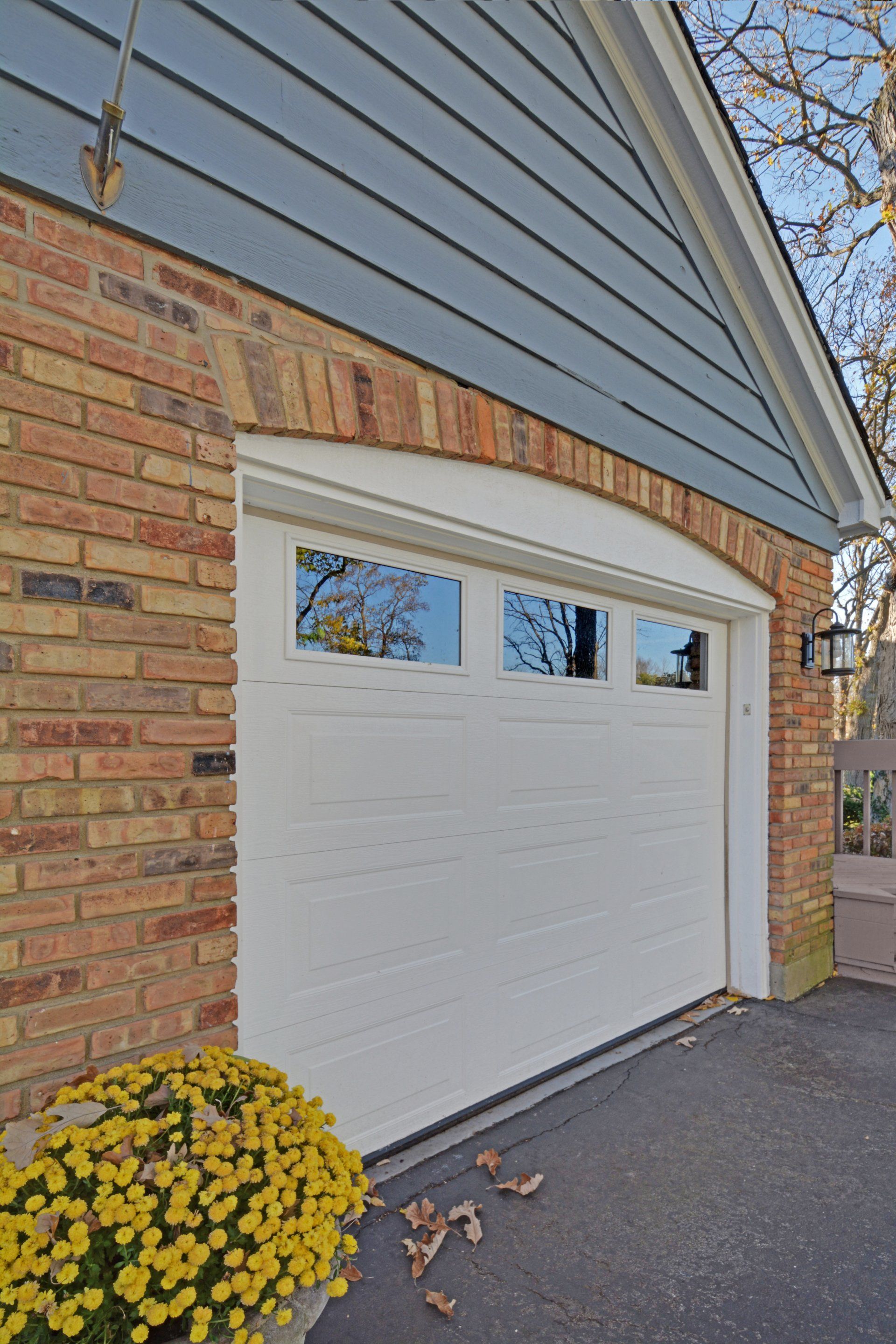 a white garage door is on the side of a brick house .
