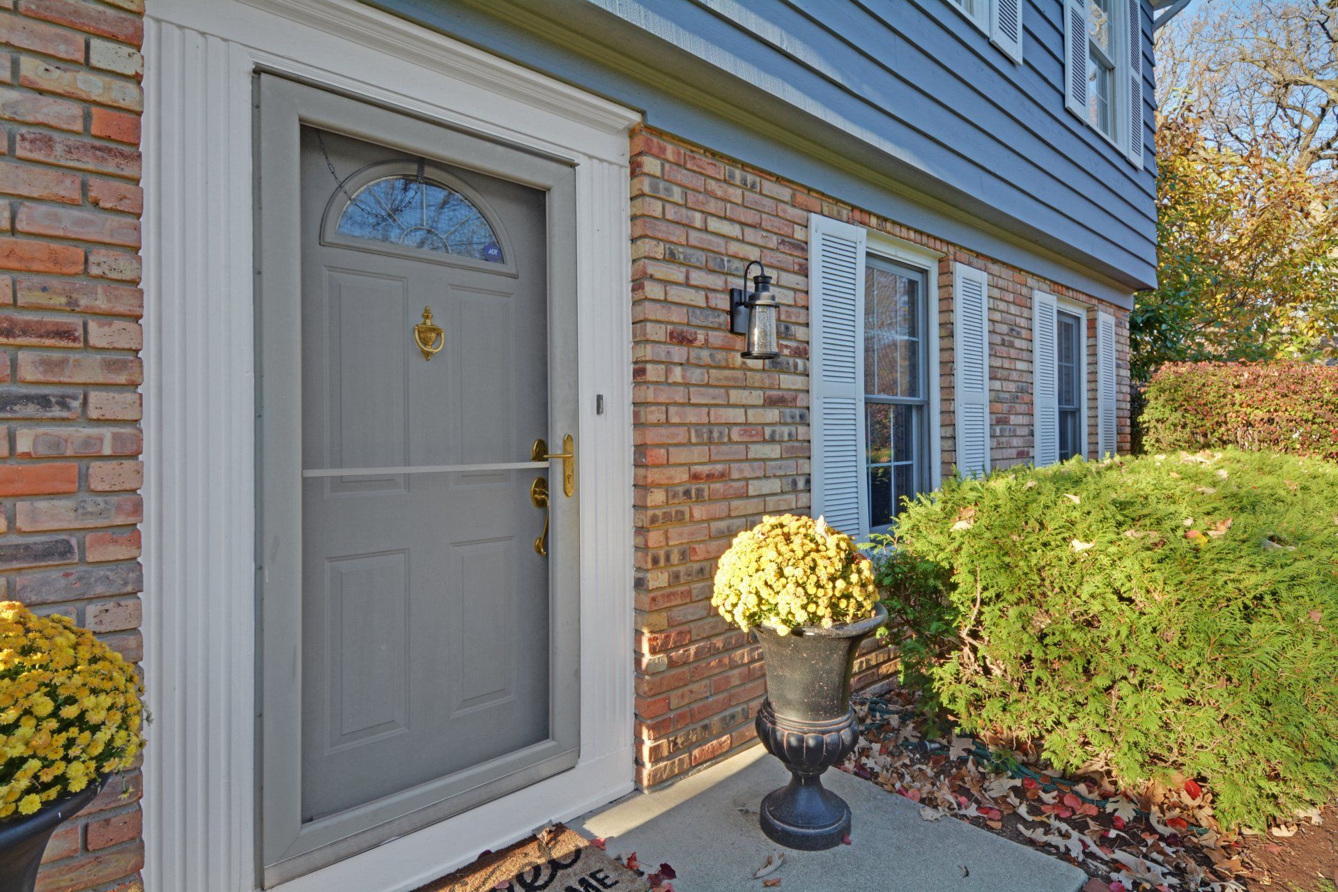 the front door of a brick house with a gray door and a white trim .