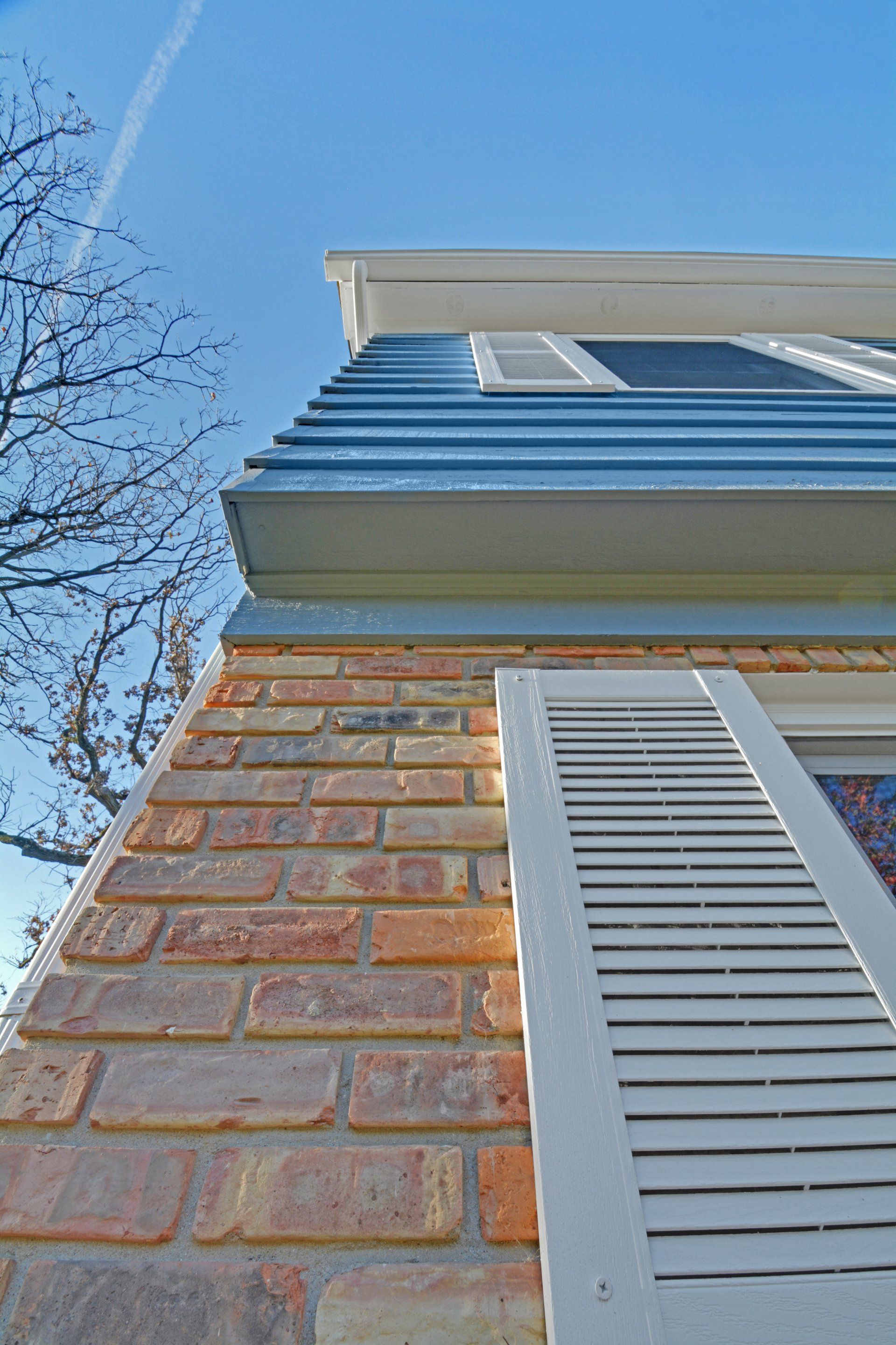 looking up at a brick building with white shutters