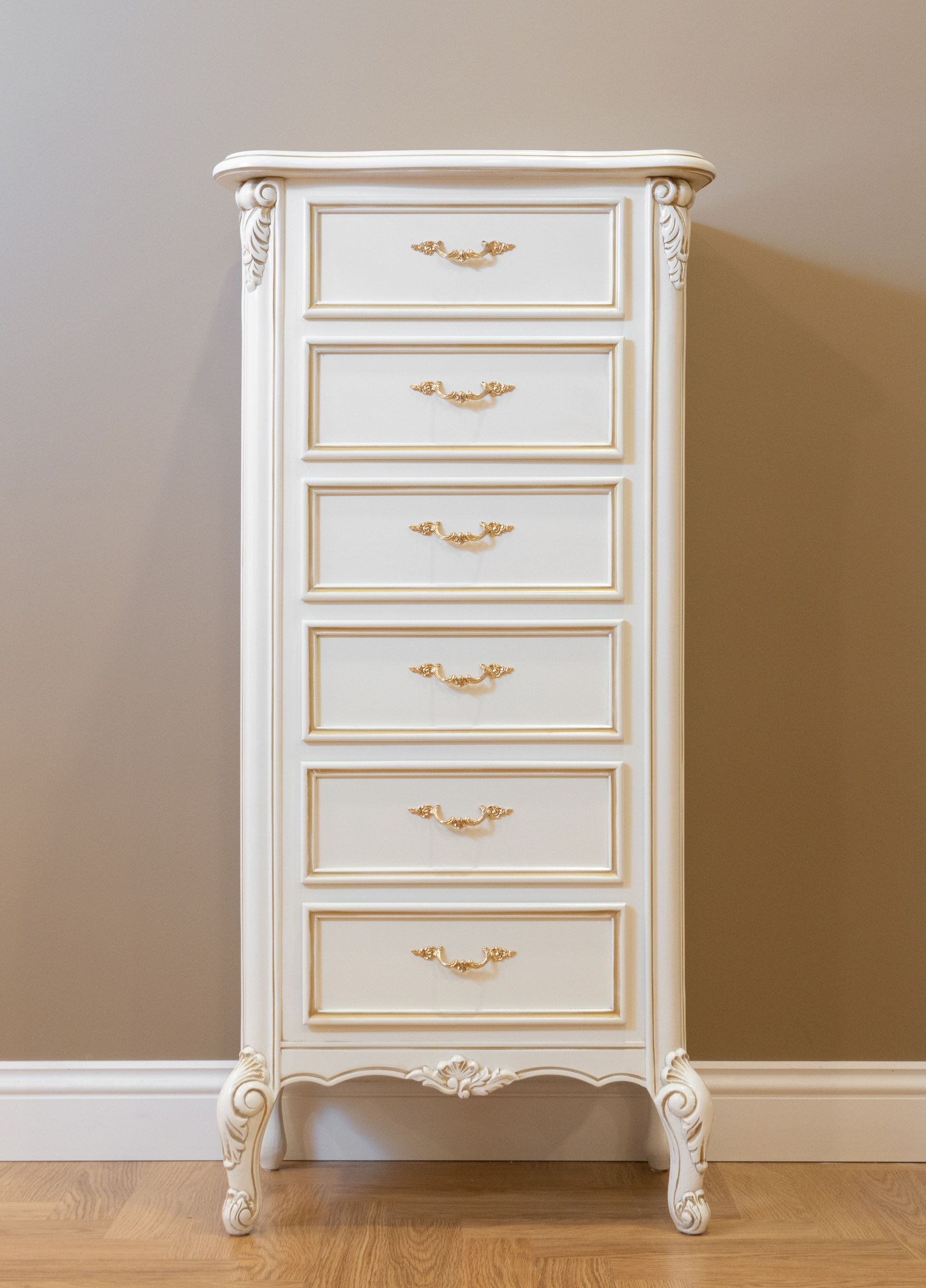 White six-drawer dresser with gold handles against a beige wall