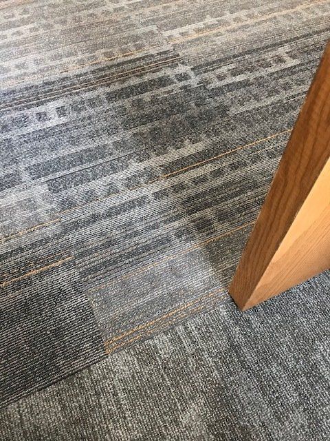 A close up of a carpeted floor next to a wooden post.