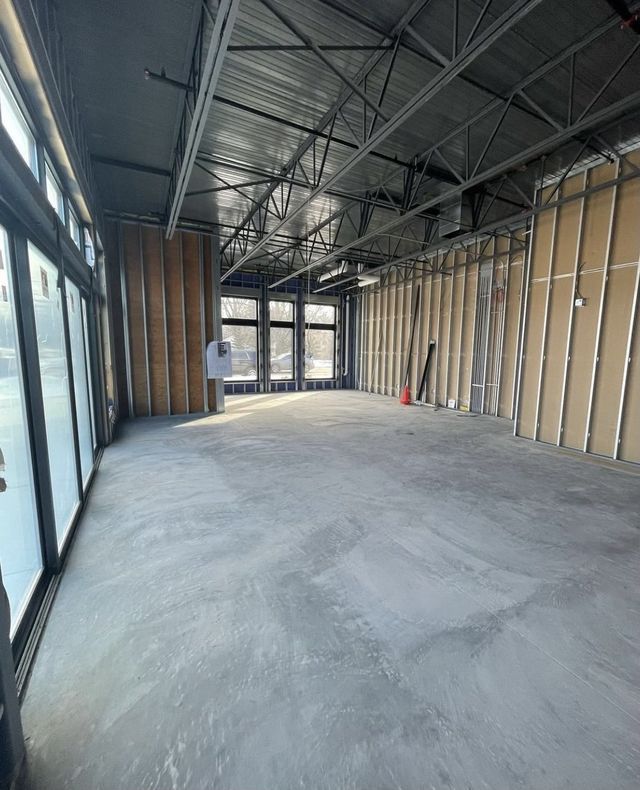 A large empty room with a lot of windows and a concrete floor.