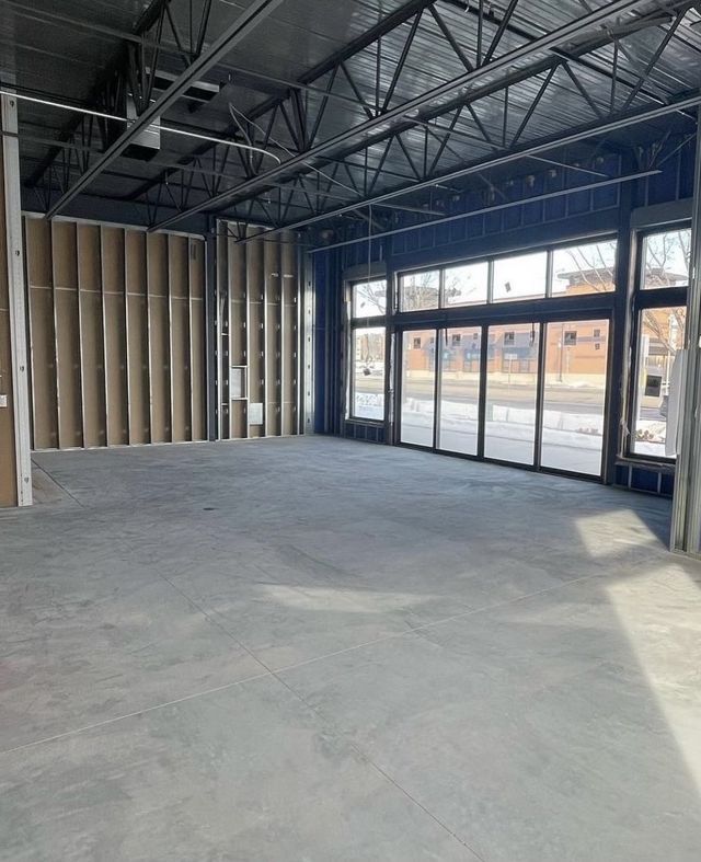 A large empty room with a lot of windows and a concrete floor.