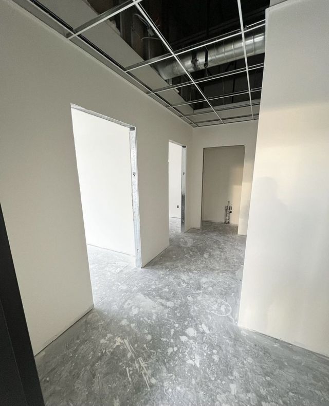 An empty room with white walls and a gray floor