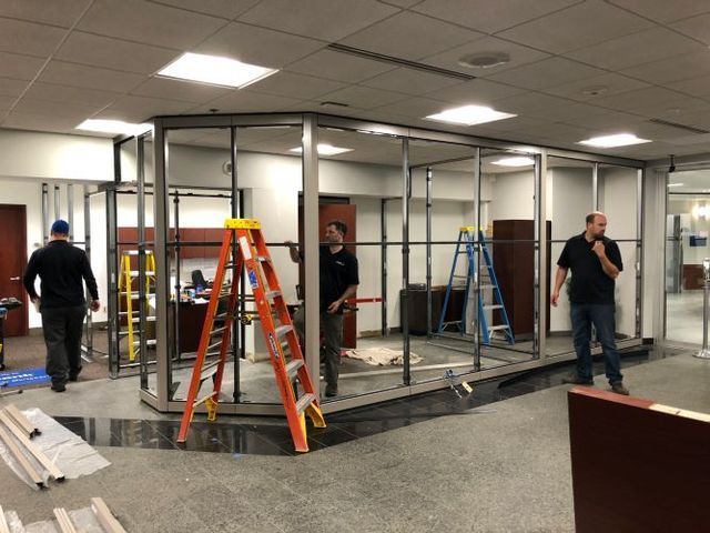 A group of men are standing in a room with a ladder.