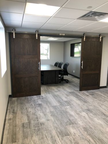 A conference room with sliding barn doors and a table and chairs.