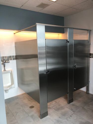 A public restroom with stainless steel stalls and a urinal.